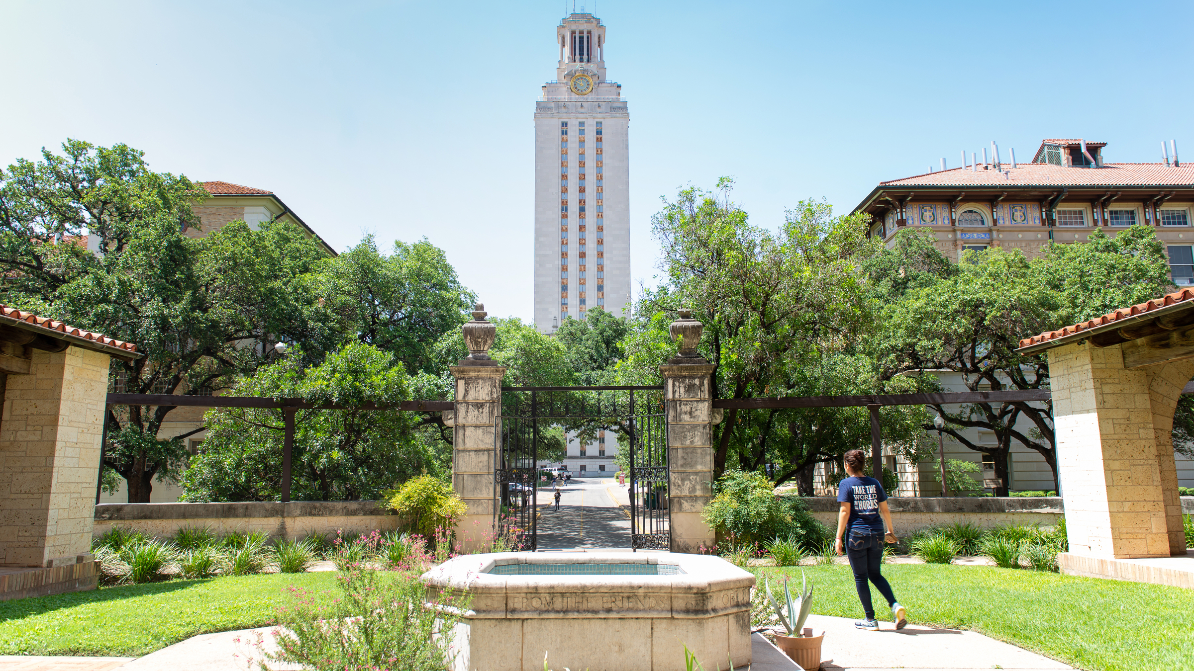 A person walks across the Gearing Hall courtyard alone near the UT Tower