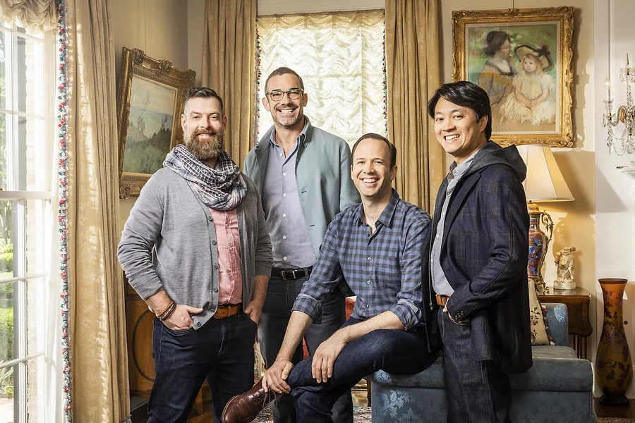 Four men smile for the camera in a room with antique and historic decor