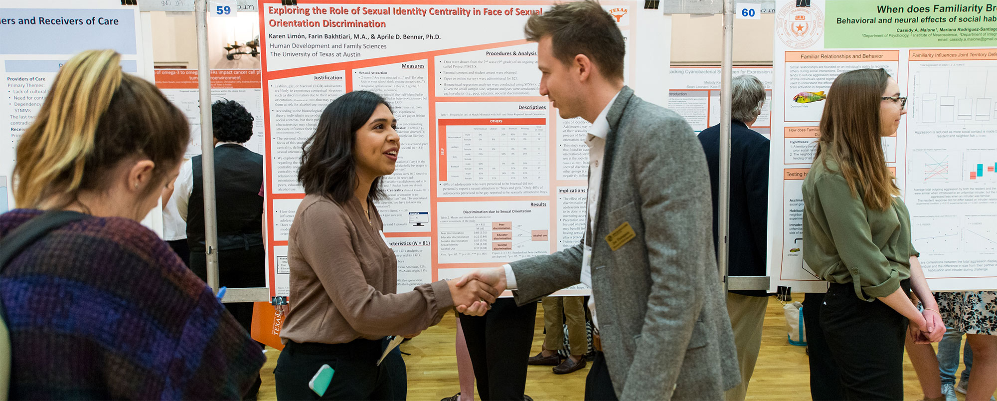Woman and man shaking hands in front of research poster
