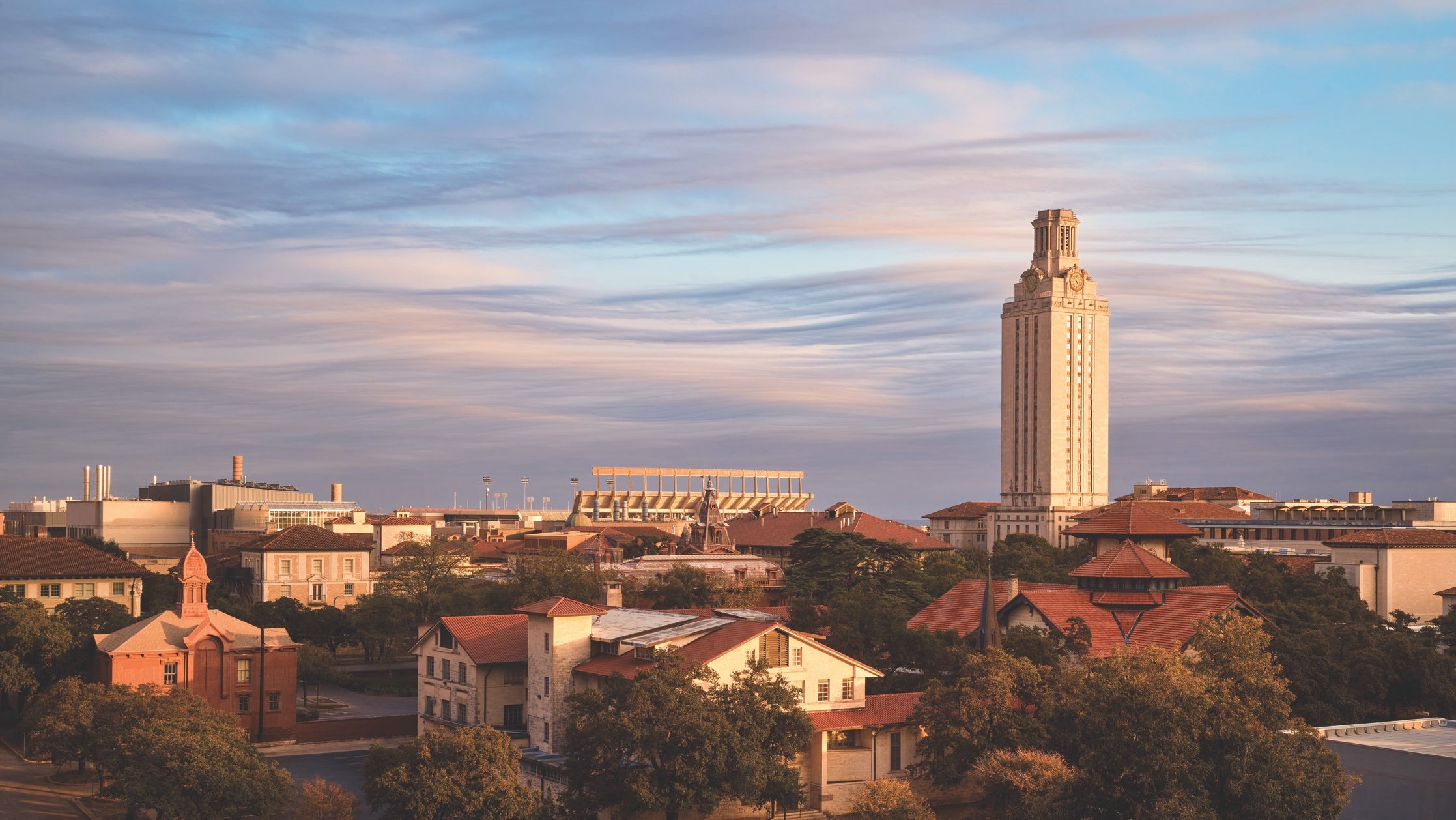The University of Texas at Austin campus early at sunset with the Tower and a building with a telescope on its roof beneath a partially cloudy sky