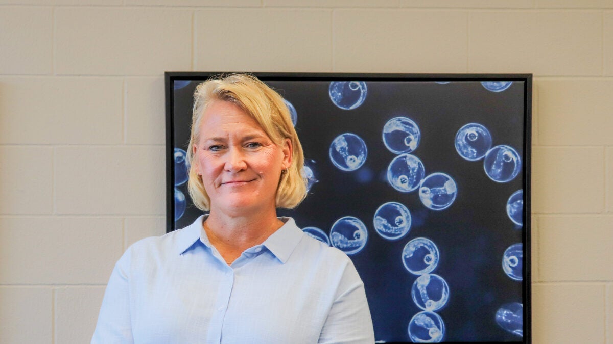 Broodstock manager Leigh Walsh stands in front of an image of flounder embryos