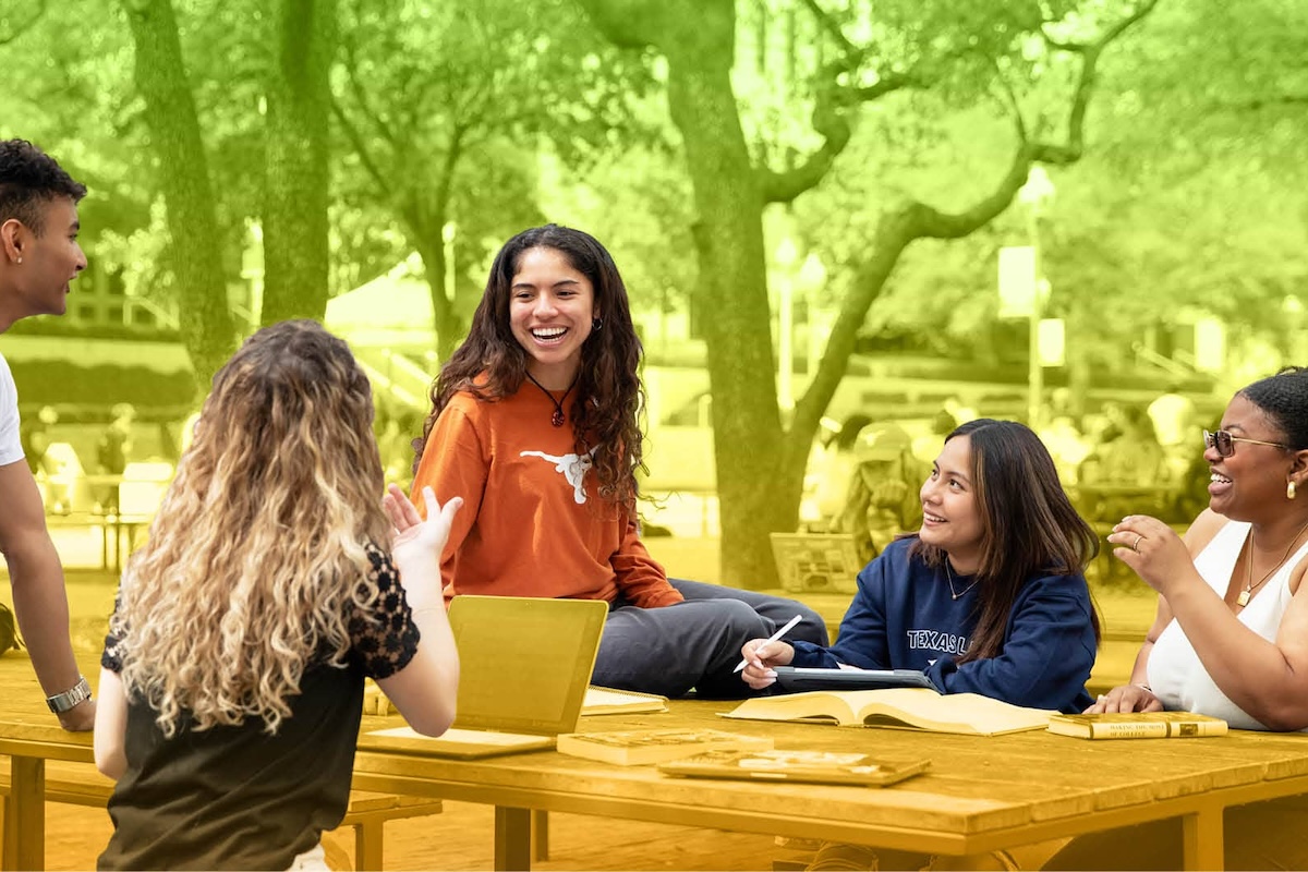 5 students laugh and chat, gathering at a picnic table on the UT campus.