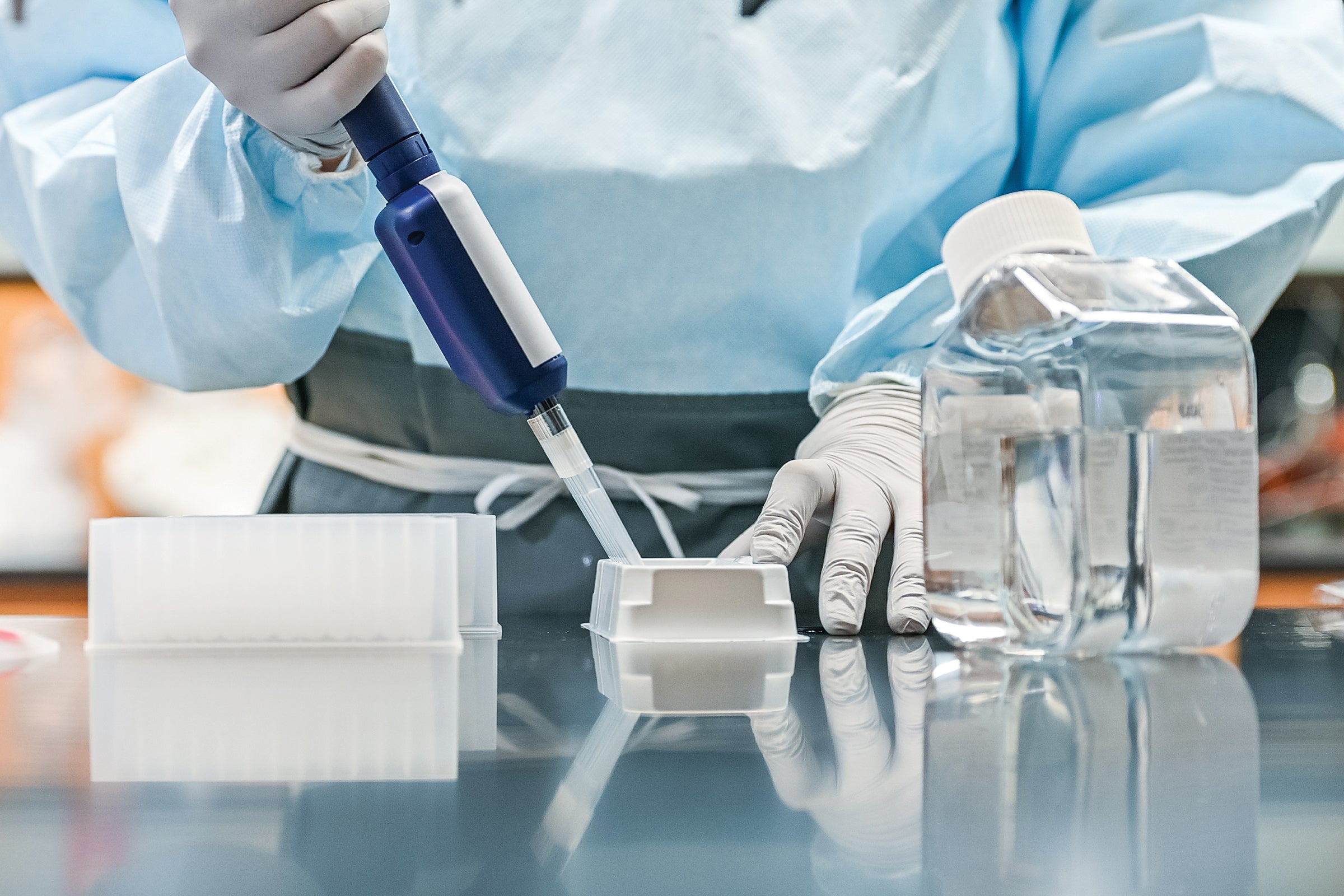 Person in lab with pippette and diagnostic tools