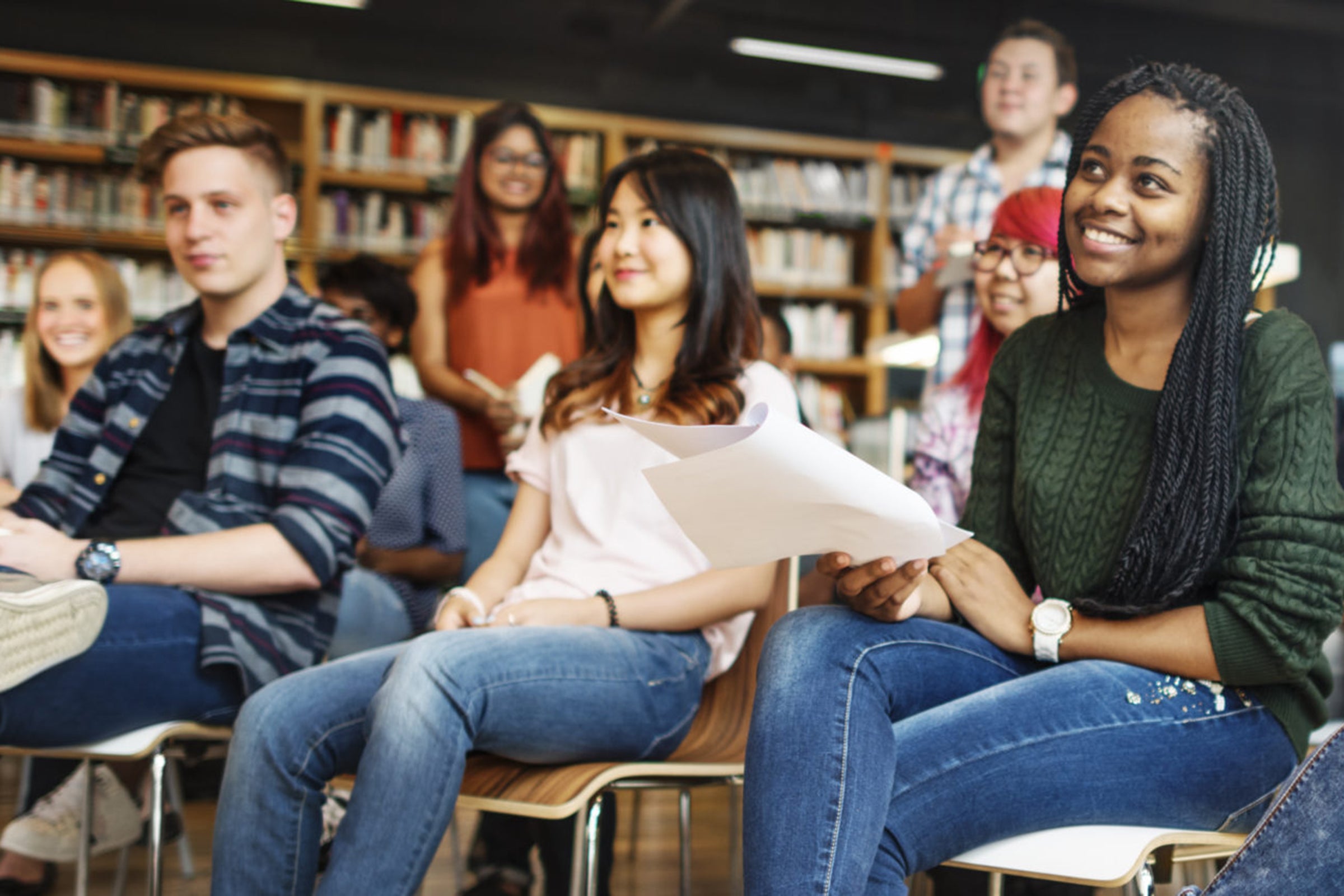 Graduate students sit and stand in rows in a library setting