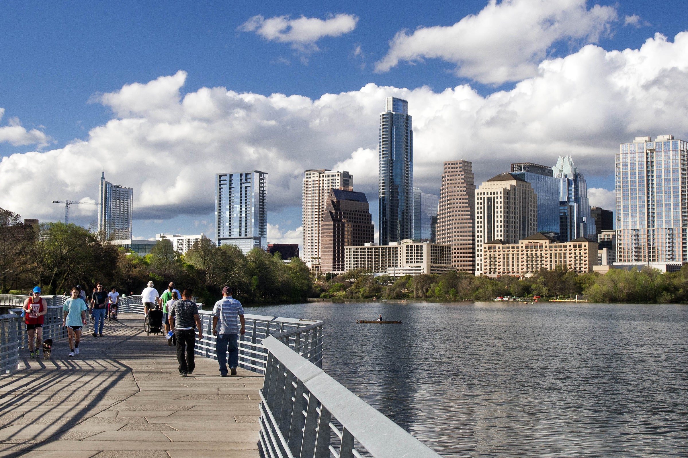 City of Austin skyline with people walking on a bridge over Lady Bird Lake