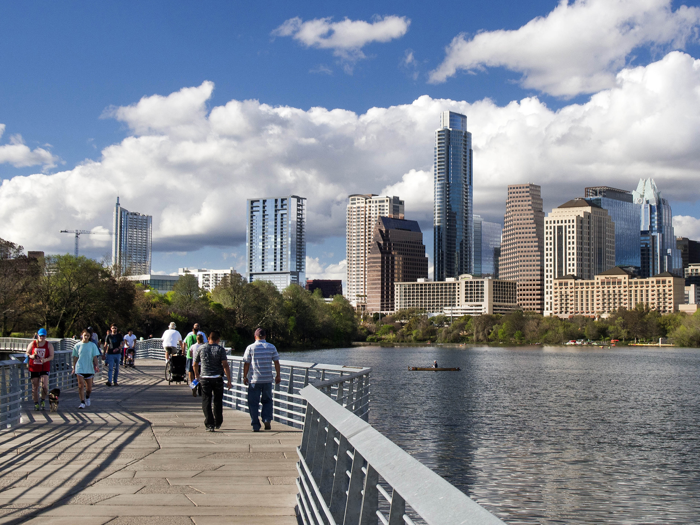 City of Austin skyline with people walking on a bridge over Lady Bird Lake