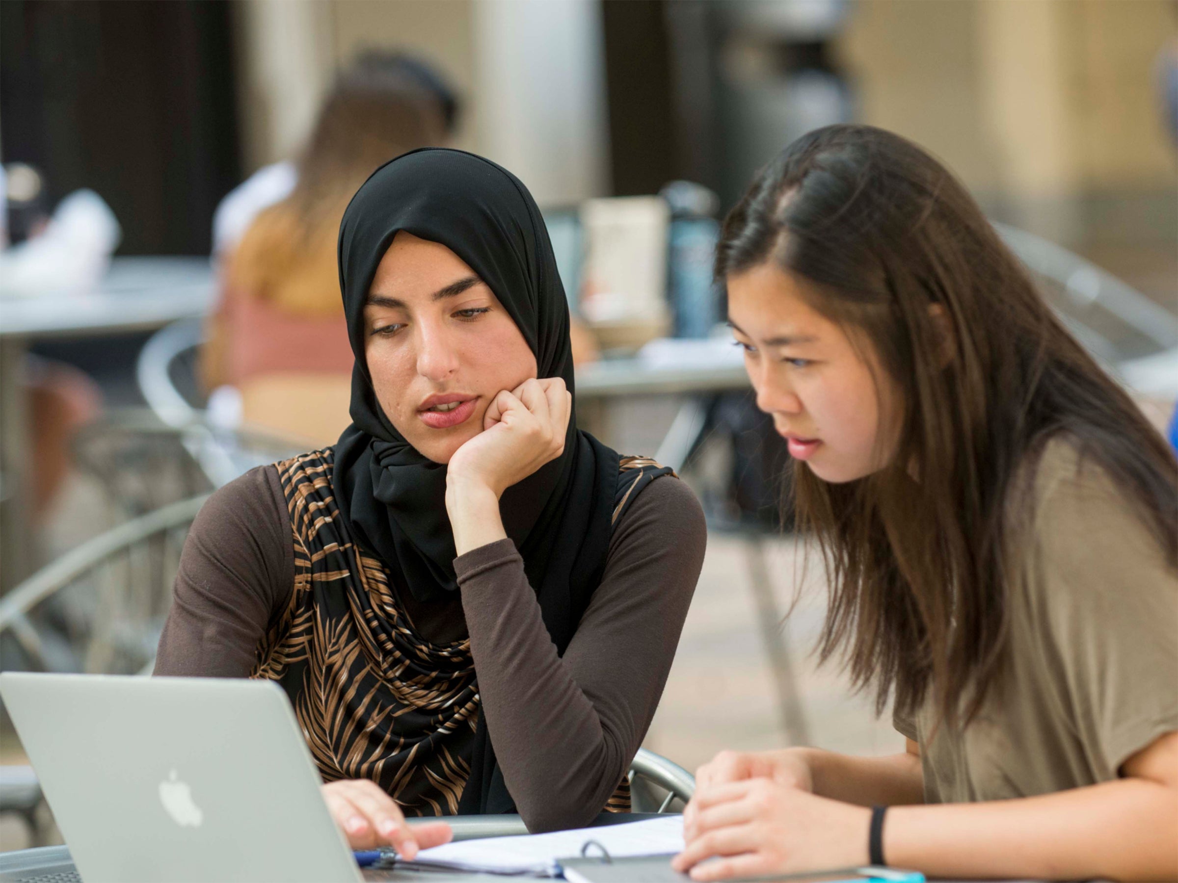 Two people sitting at a table and looking at a computer outside the Texas Union.