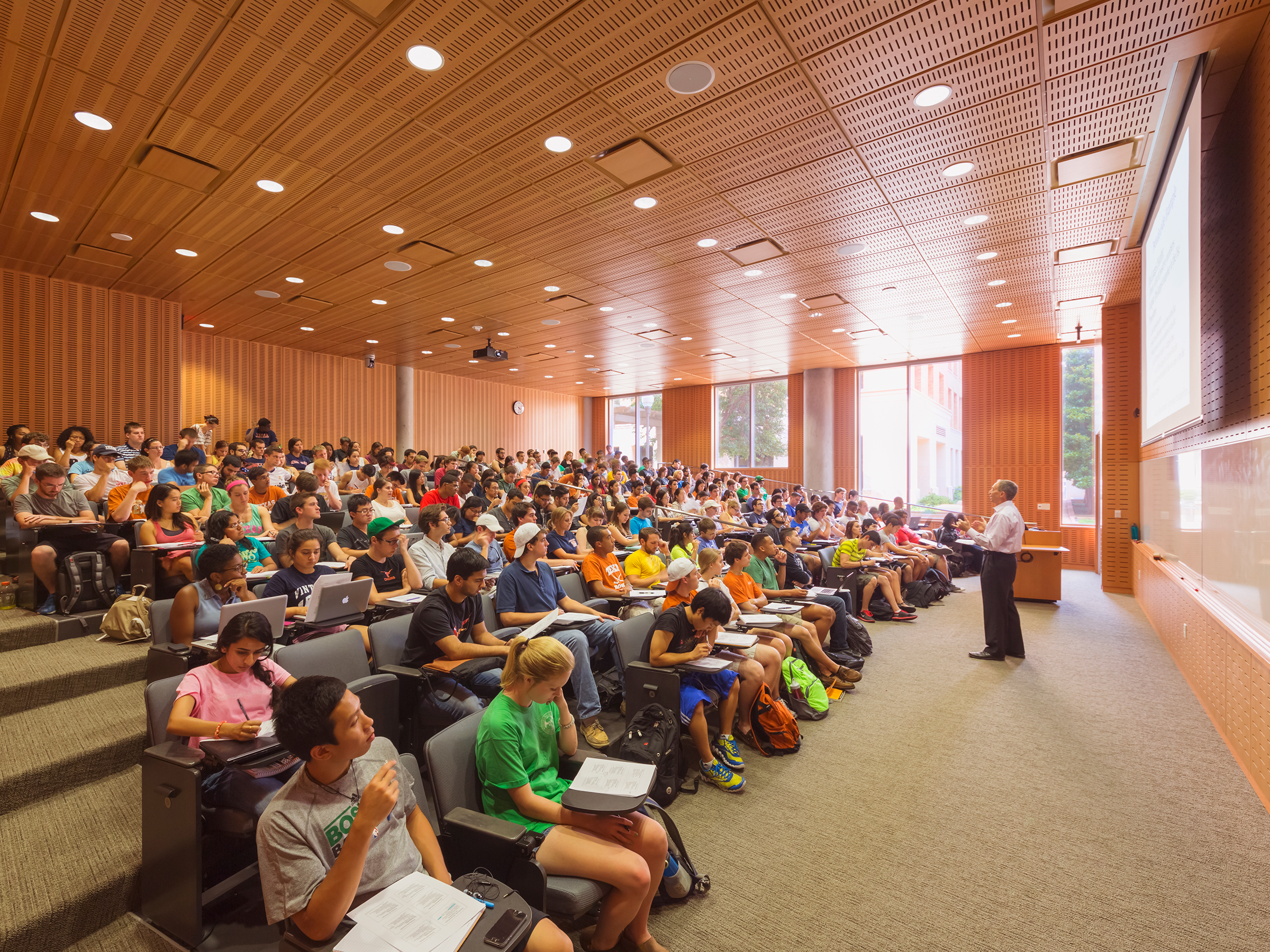 Photo of a professor standing at the front of an auditorium teaching a large class in computer science.