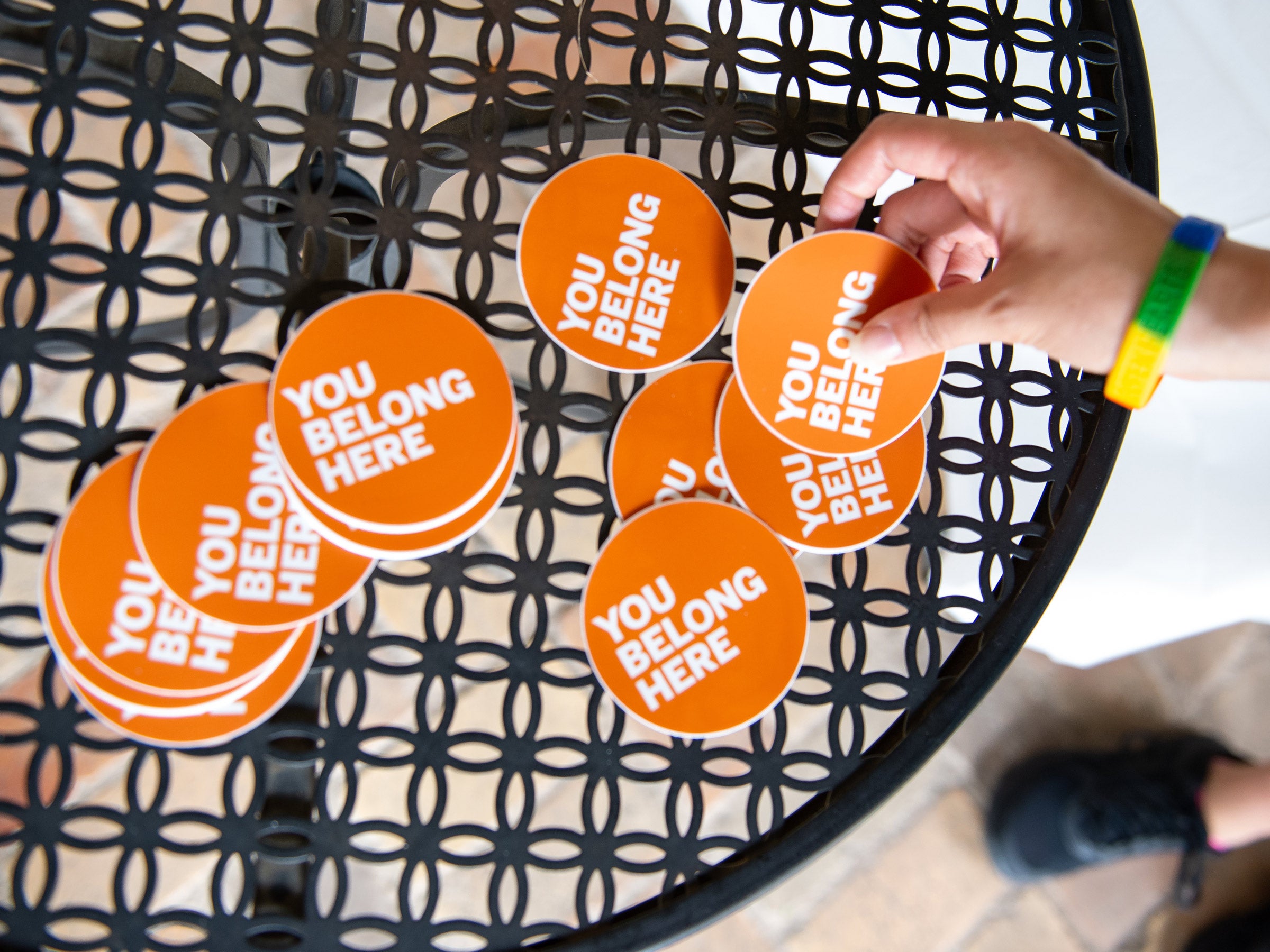 A close-up photo of stickers on a table that read "You Belong Here."