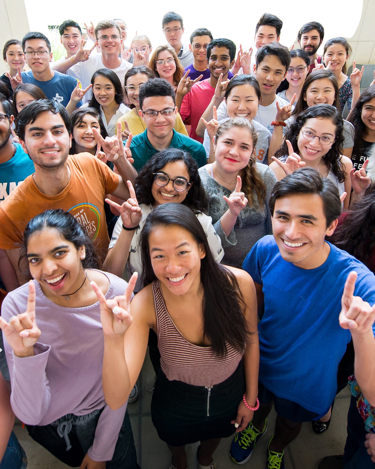 Group of FRI students smiling with Hook ’em hand gestures.