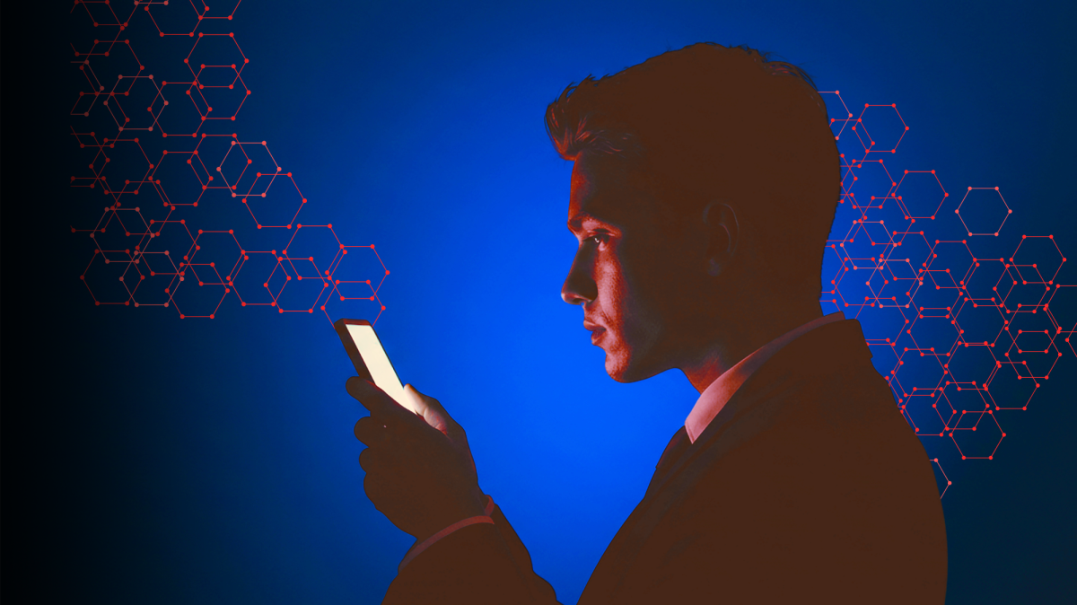 A person in a dark room stares at the glowing screen of a smart phone