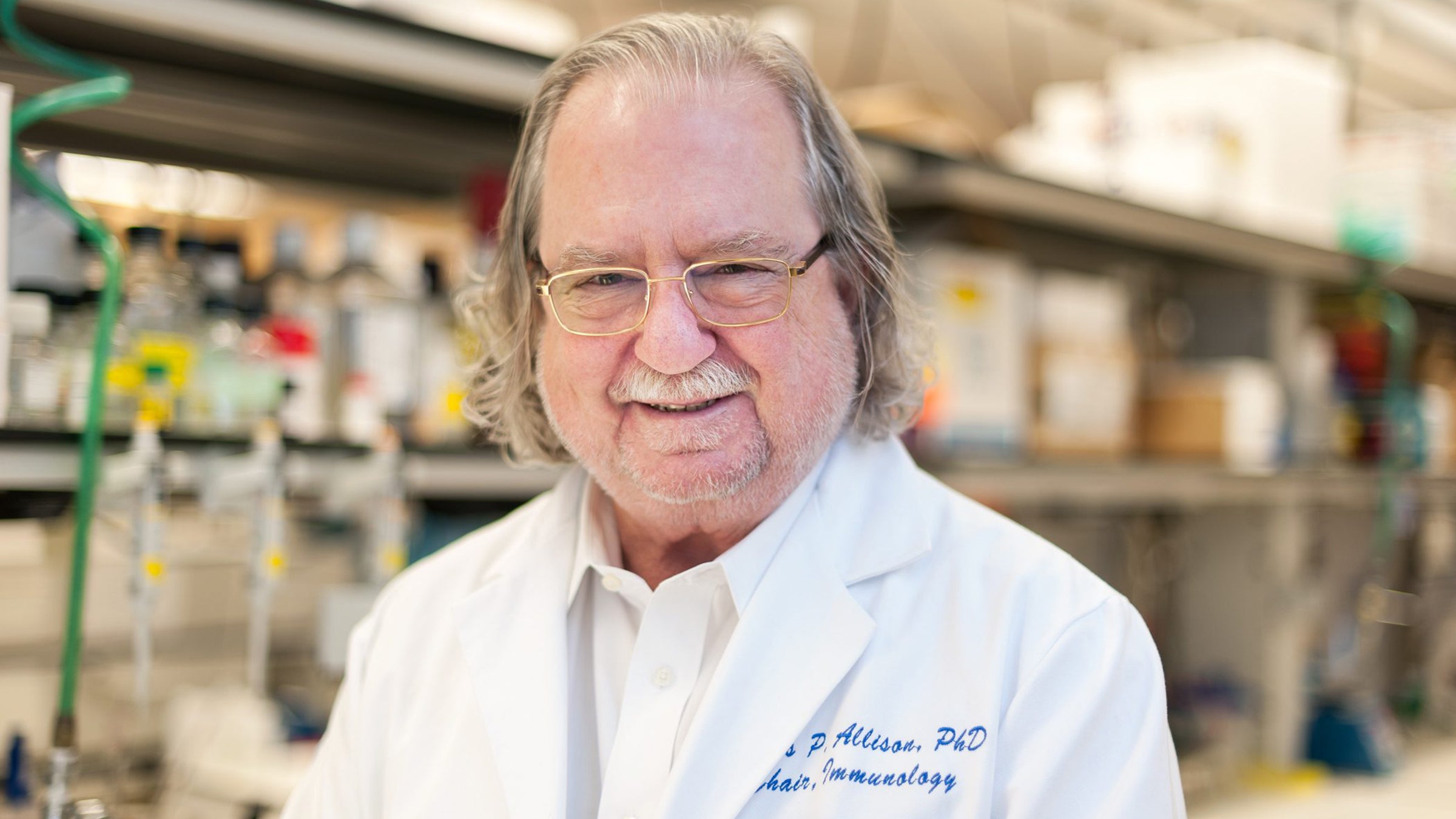 James Allison in a lab coat standing in a laboratory