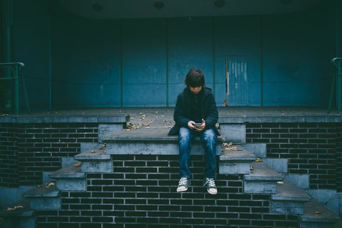 A boy sitting on a set of brick steps