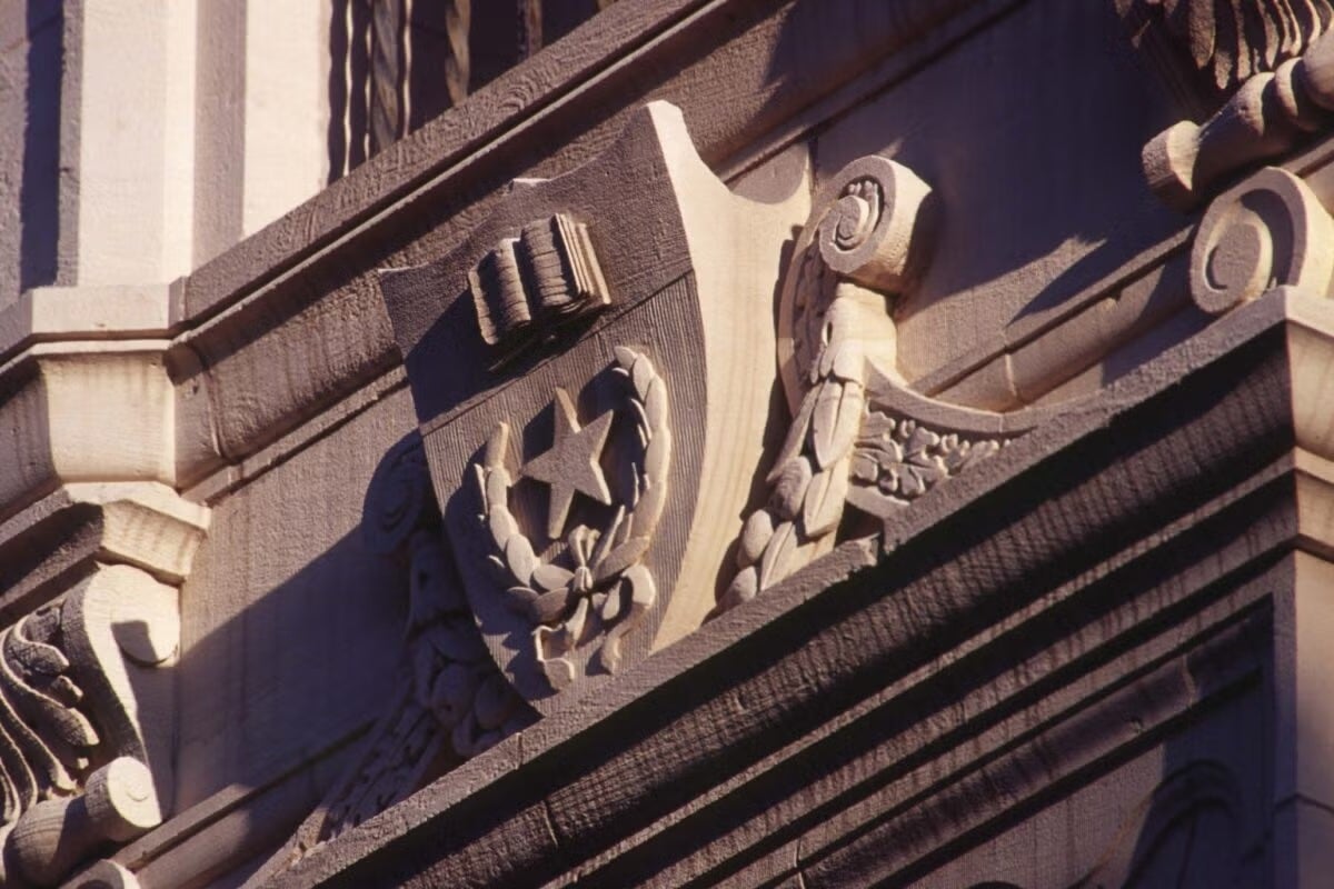 Stonework of the University of Texas at Austin seal with the shield on a building.