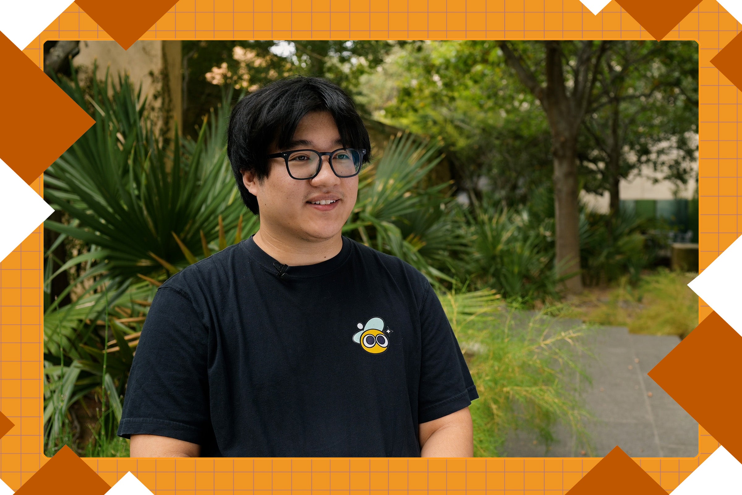A young man in glasses and. at-shirt smiles while standing outdoors. Burnt orange graphics frame his image.