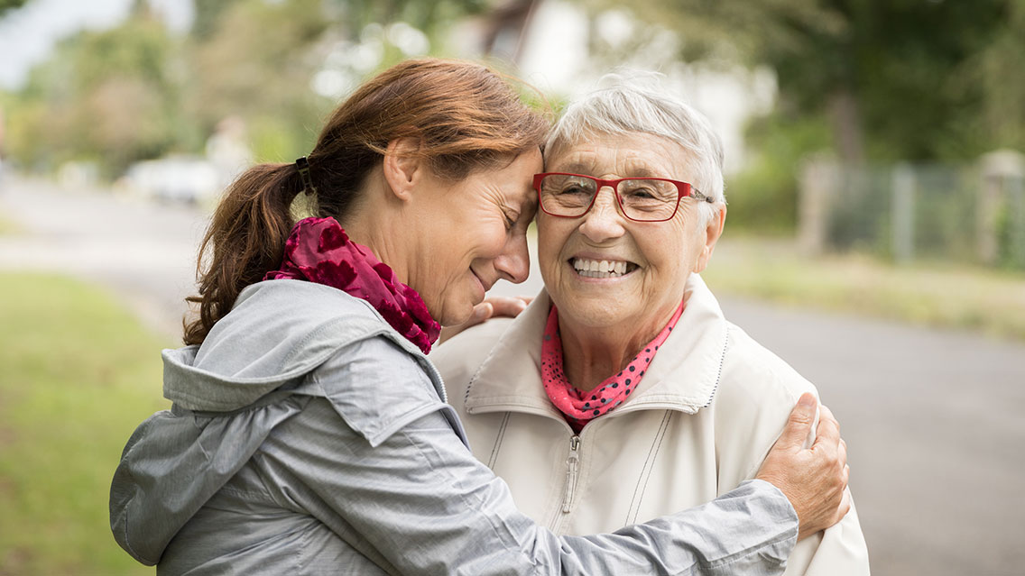 An elderly woman, right, is embraced by a younger woman, left. 