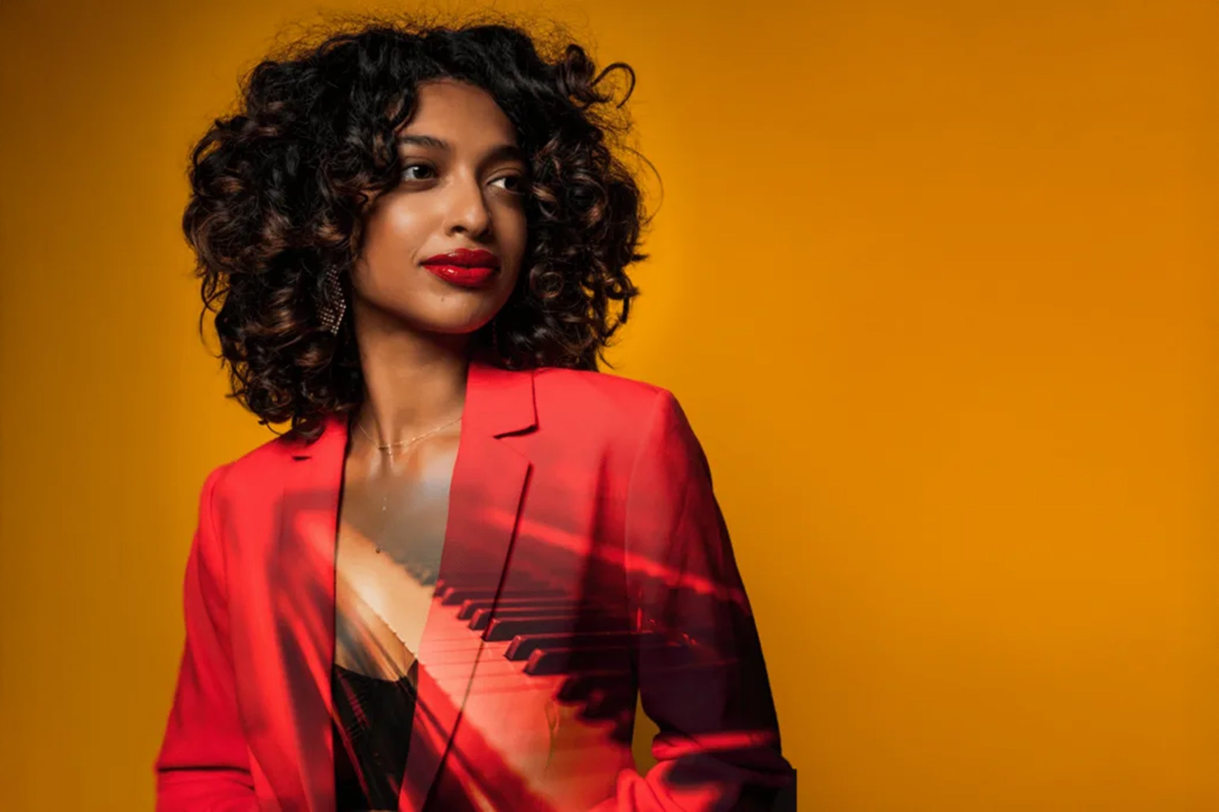 Image of Chelsea de Souza wearing a red blazer over a black top and an image of a piano keyboard superimposed over her.