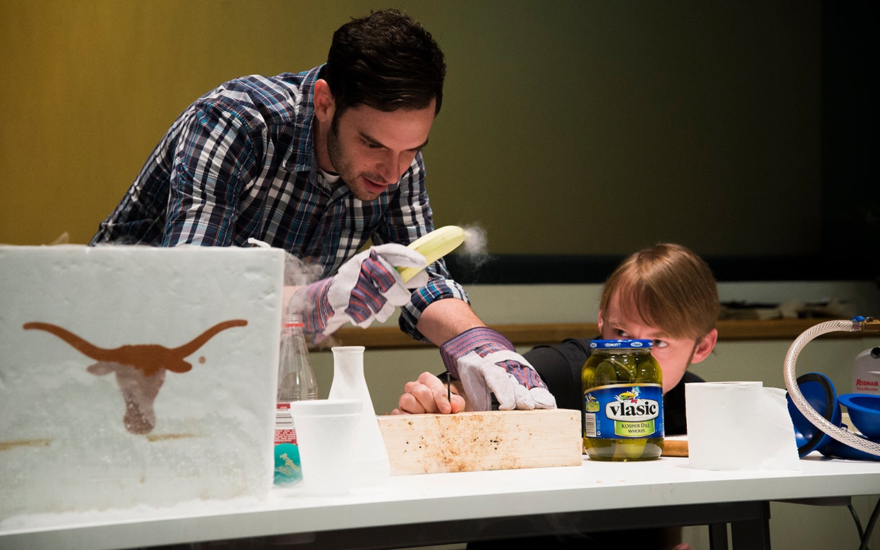 Jeremy Paster attempts to hammer a nail with a frozen banana as Tom Hartsfield warily holds the nail.