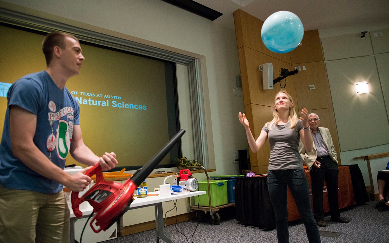 Scott Luedtke uses a leaf blower to lower the air pressure above a ball, causing it to levitate over Tess Bernard. Austin Gleeson observes from the sidelines.