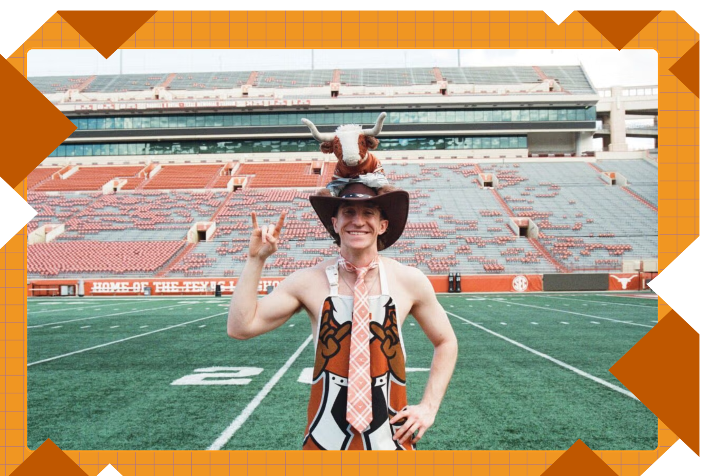 A young man in a hat with a stuffed Longhorn stands on the empty UT football field bare-armed in a burnt orange get-up flashing the hook 'em horns.