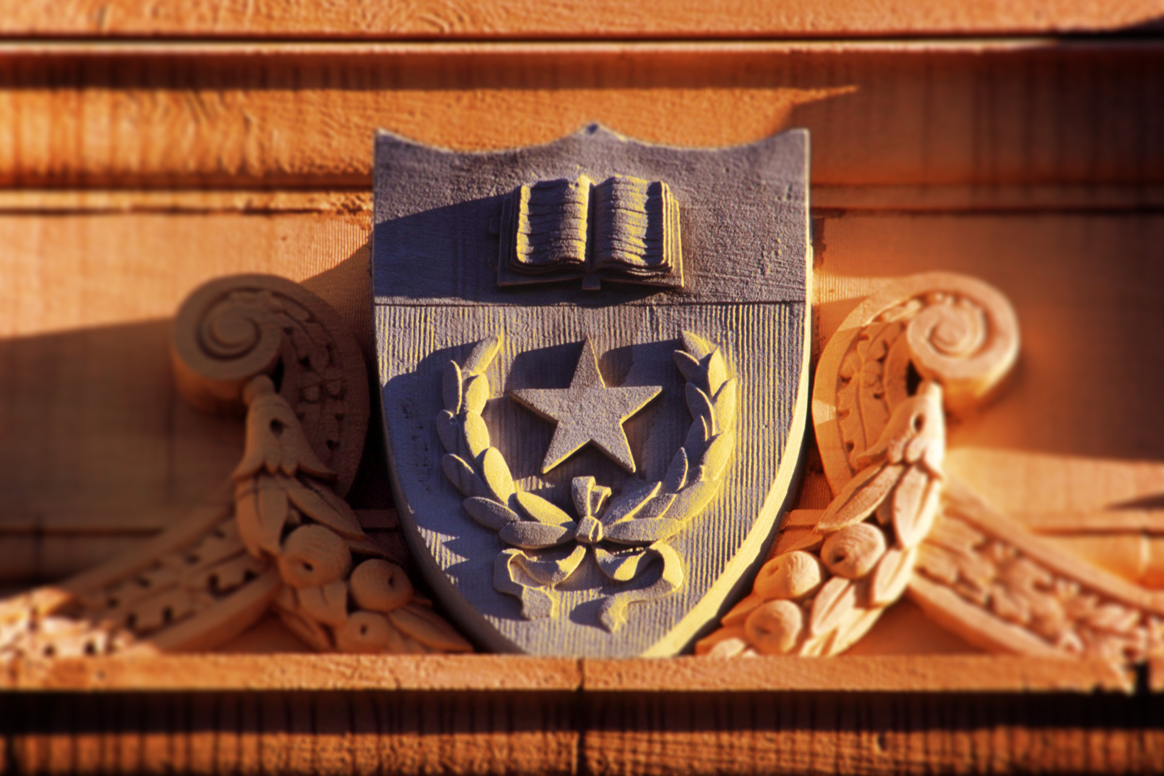 Architectural detail featuring university shield on orange tinged background