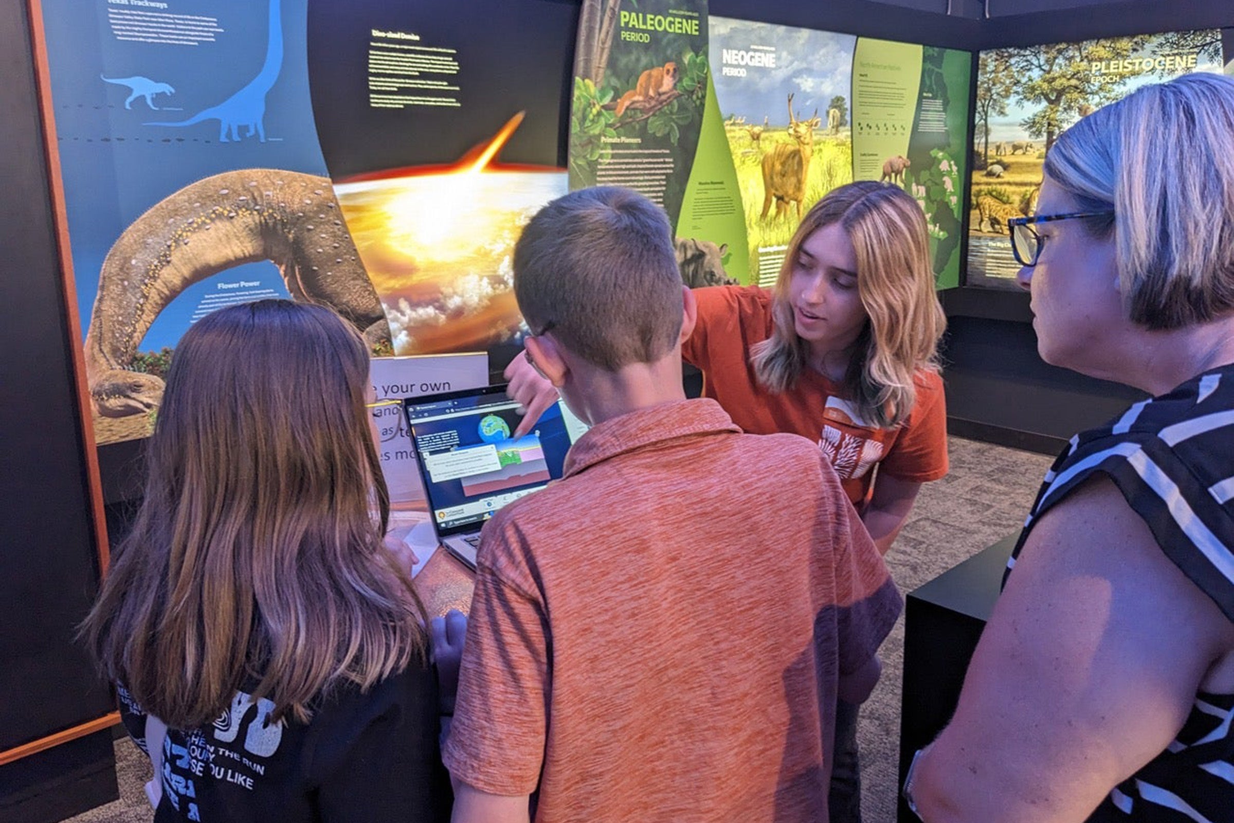 Museum staff person shows earth display to three museum guests.