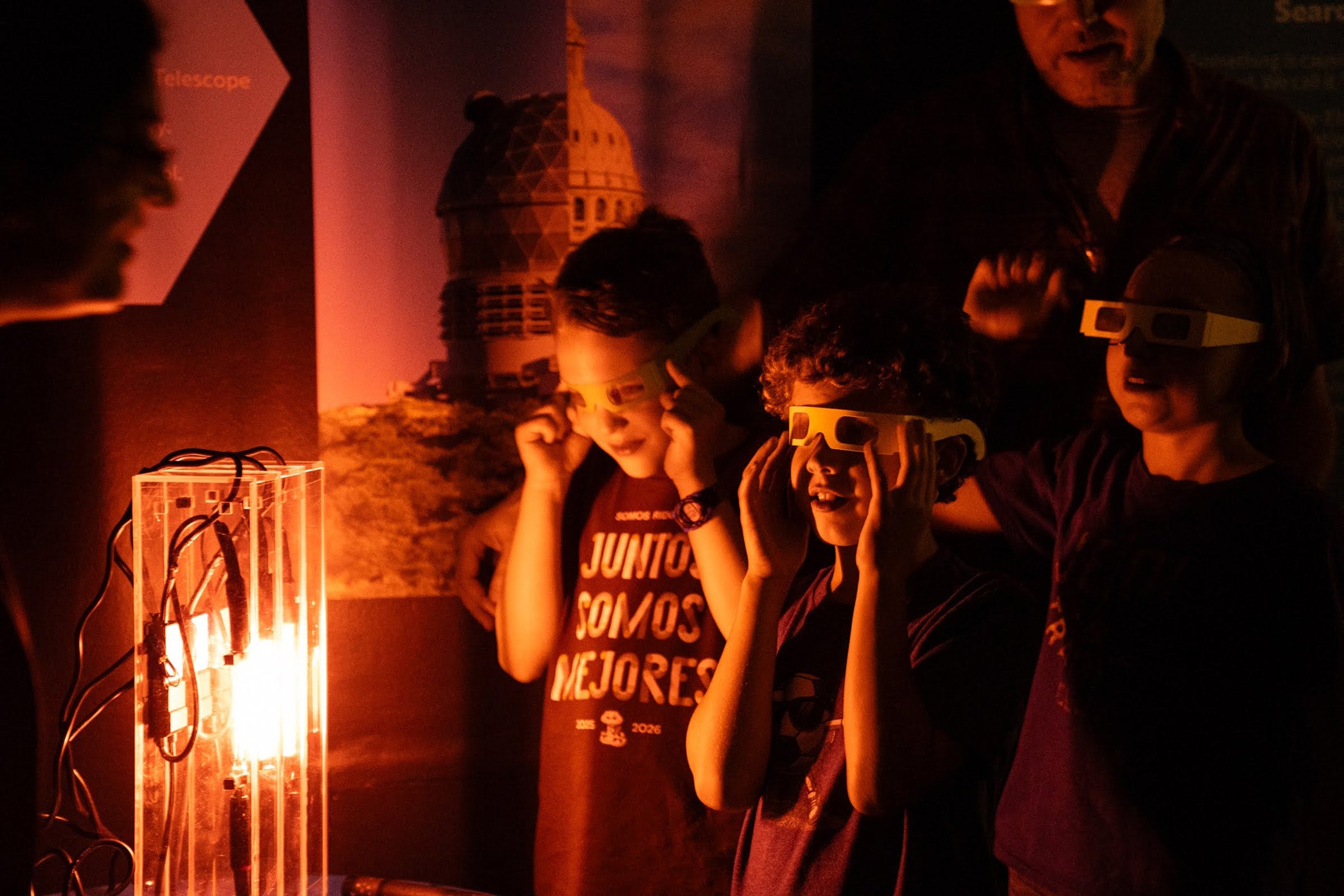 Three children wearing saftey glasses watch a bright light