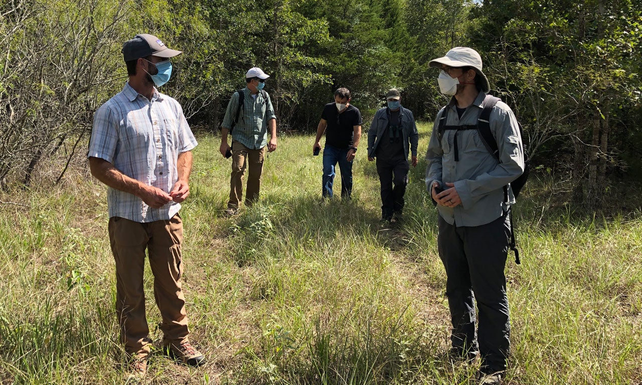 Five people stand in a field in outdoor gear