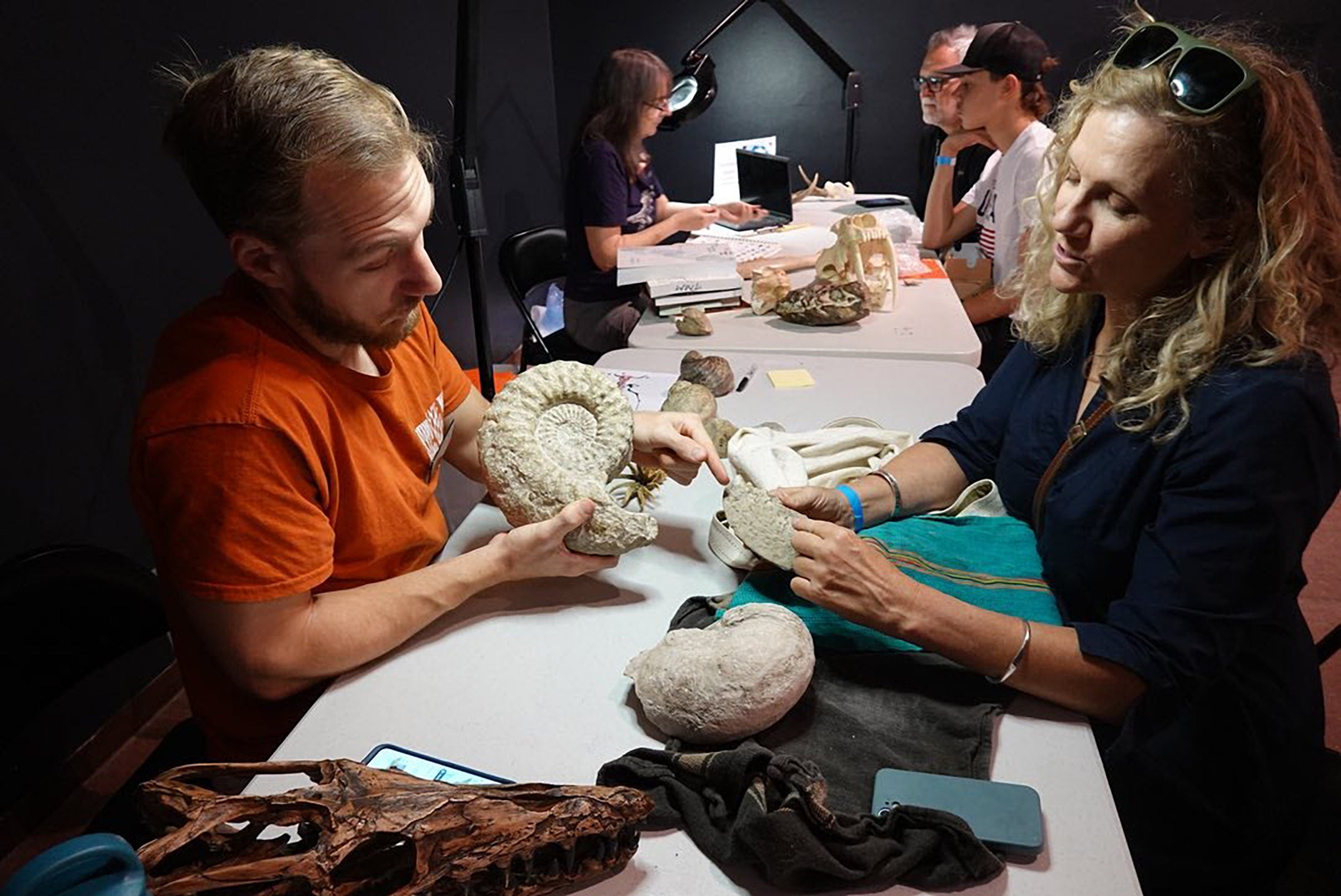 Two people on either side of a table examine a fossil.