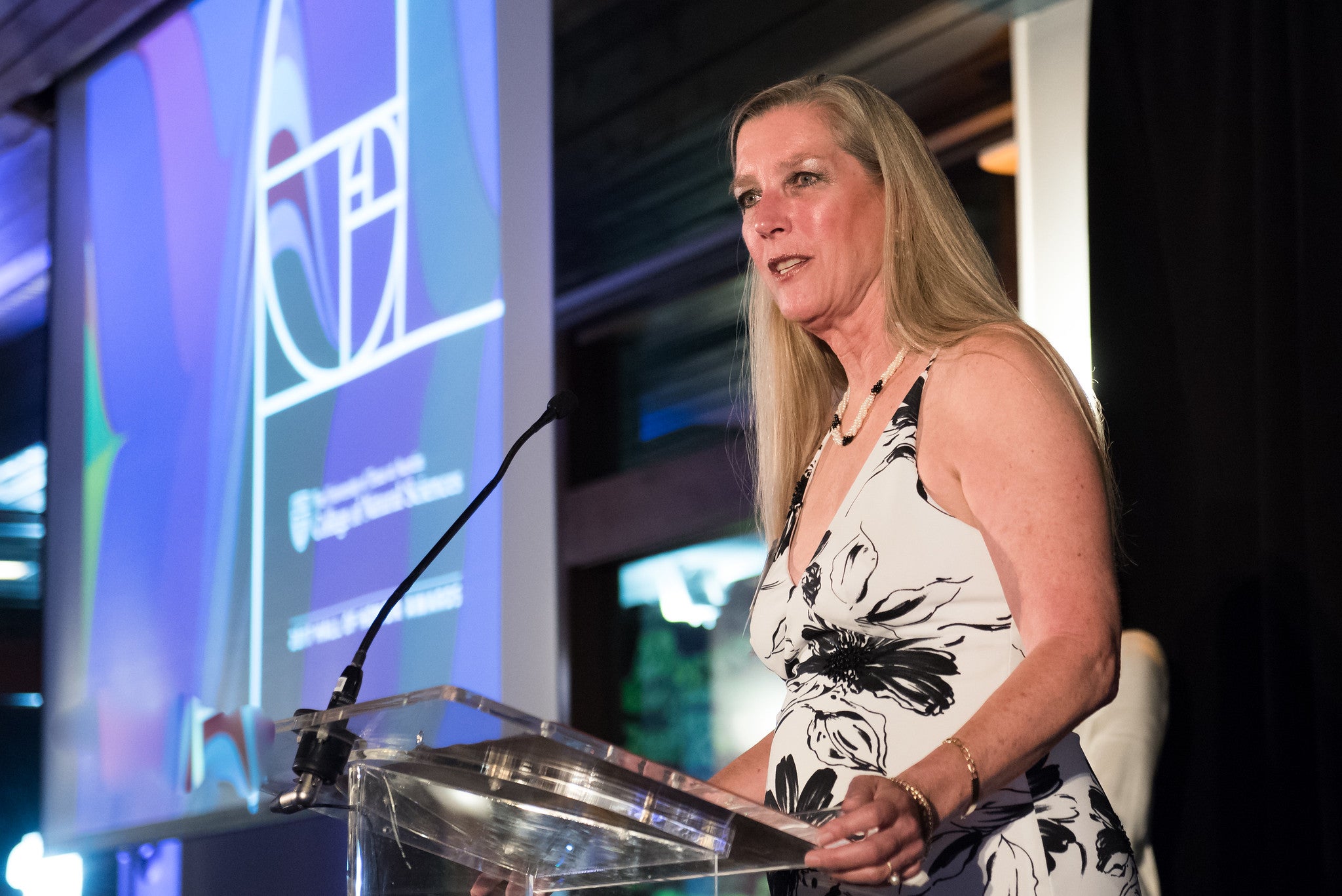 Gail Lewis at a podium in evening wear accepts an award