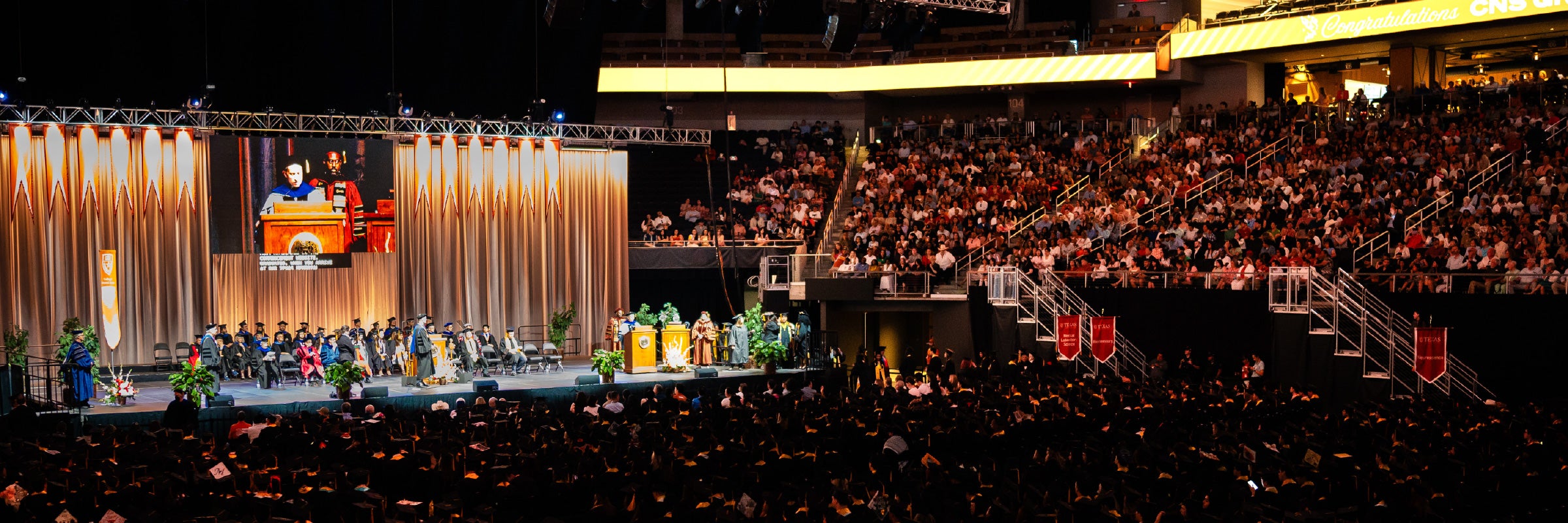 Stage with speakers and auditorium full of graduates and guests