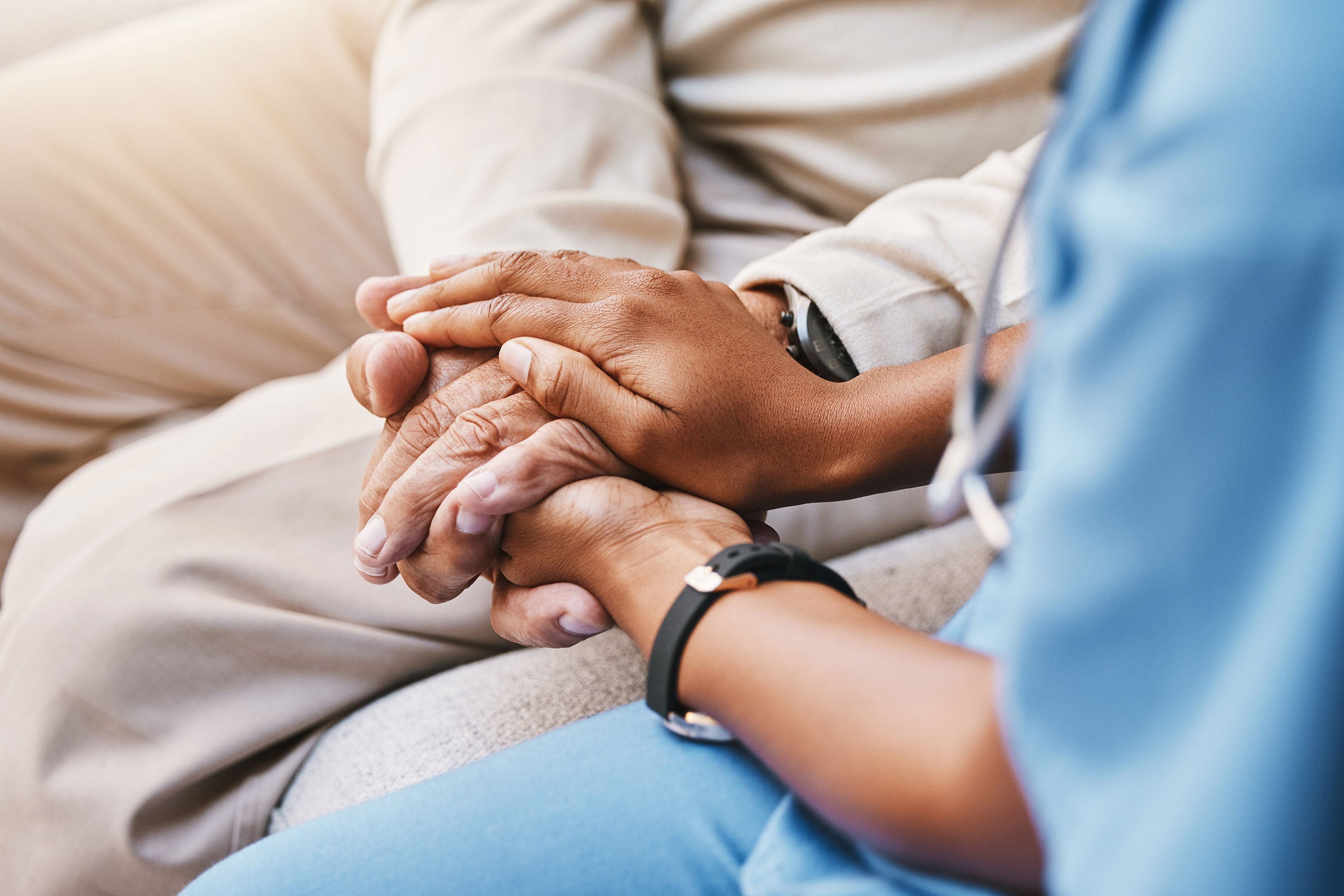 Two people hold hands, one wears blue doctor&#039;s scrubs.