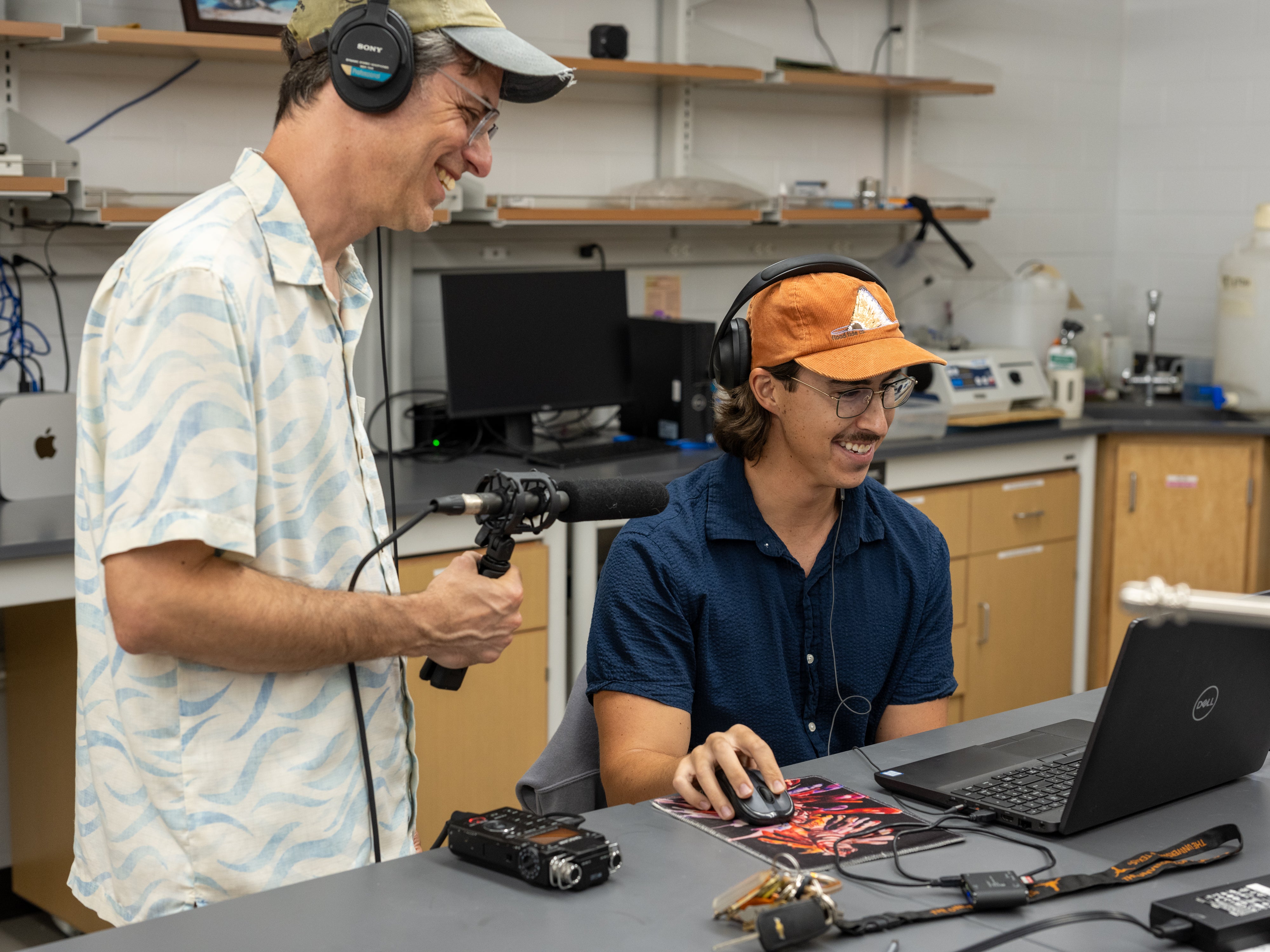 A man with a microphone interviews a scientist who is looking at a laptop