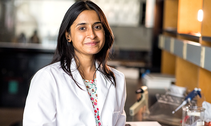 Jayashree (Jay) Srinivasan in white lab coat at her laboratory bench