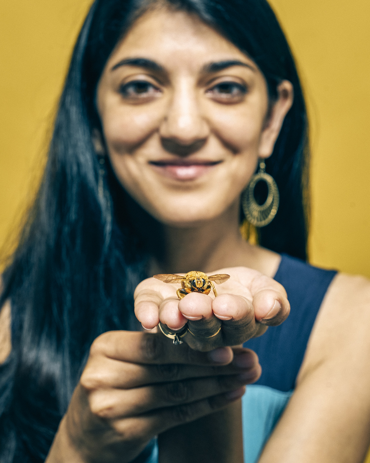 A woman holds a bee in her oustretched hand