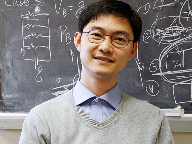 Keji Lai stands in front of a chalkboard with equations