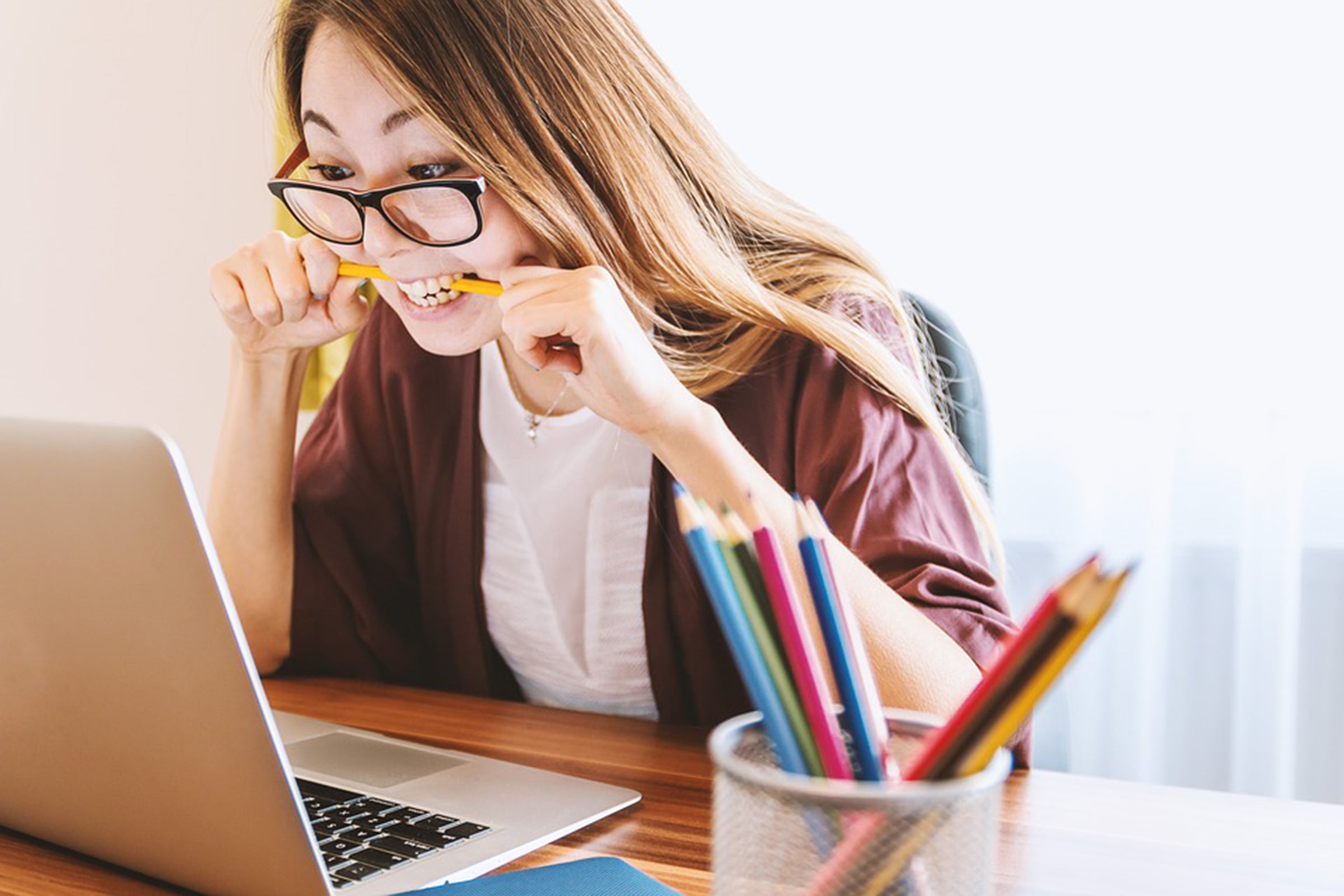 Girl is biting pencil while looking at laptop. Image from Wikimedia Commons.