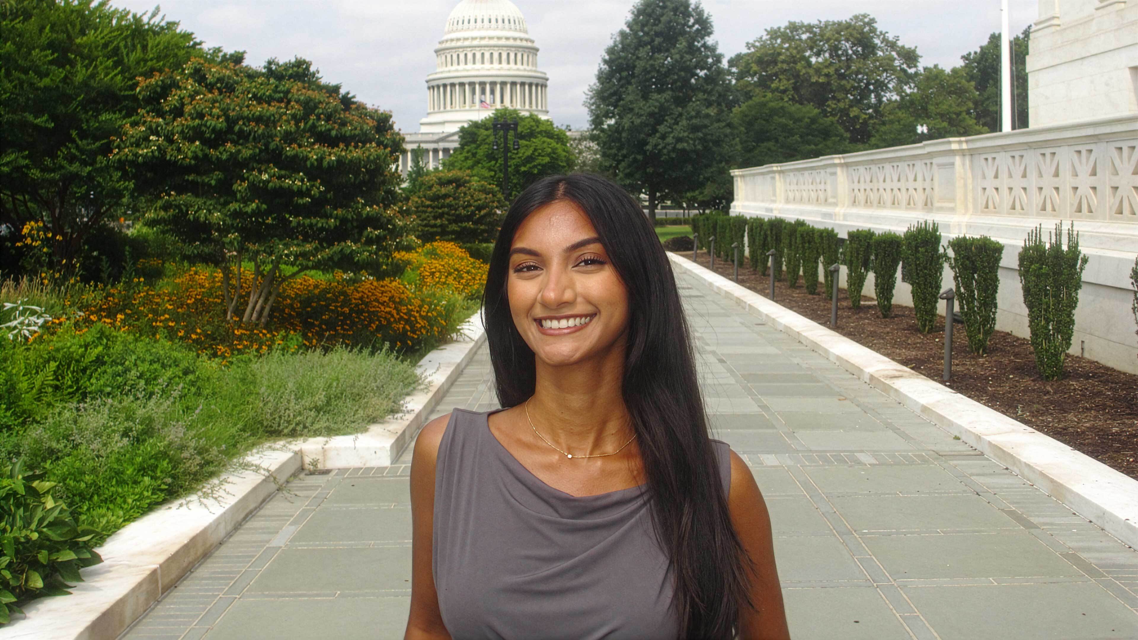 A young woman stands in front of the U.S. Capitol building in Washington, D.C.