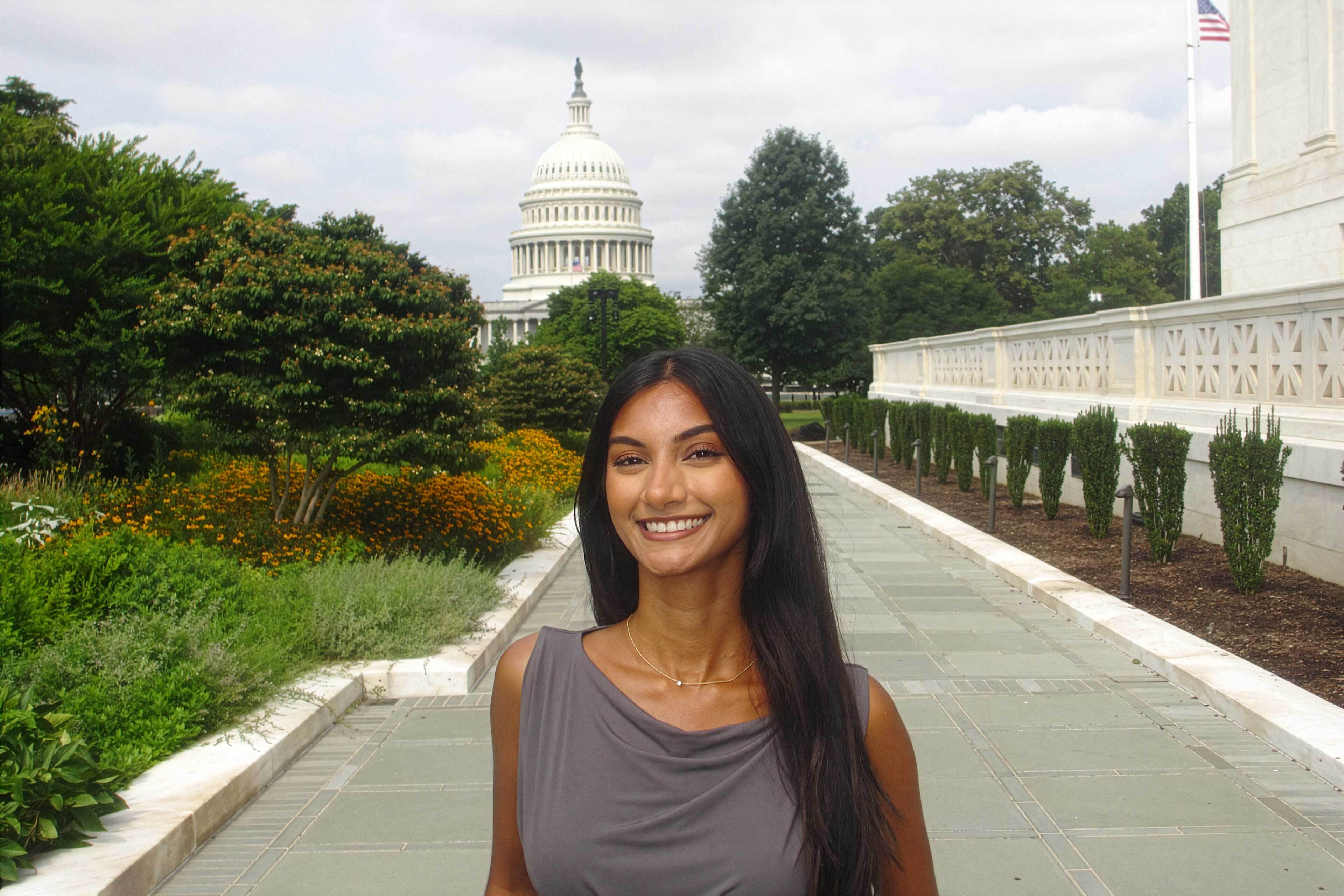 A young woman stands in front of the U.S. Capitol building in Washington, D.C.