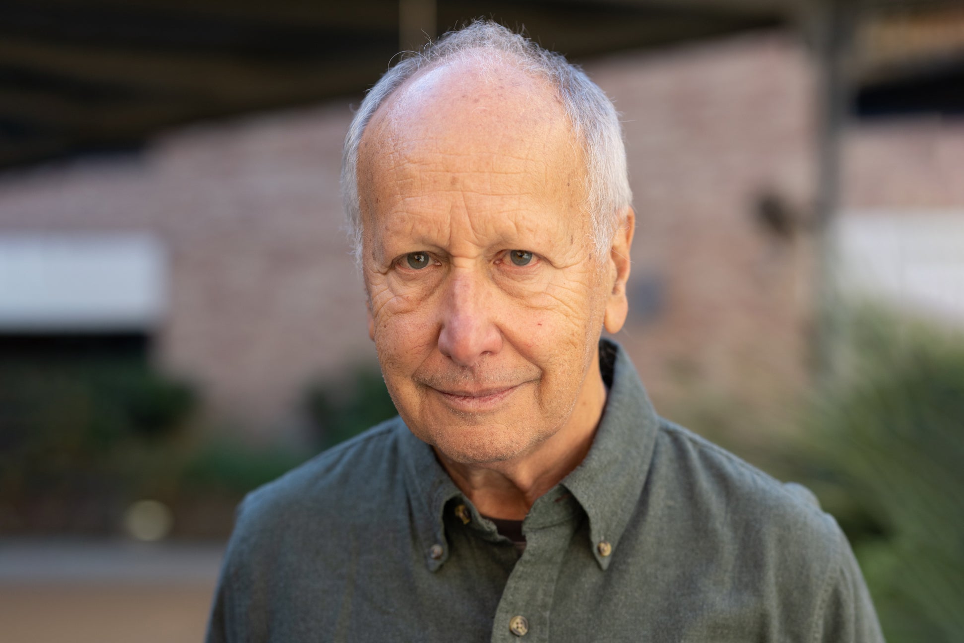 Luis Caffarelli in a collared shirt standing in an outdoor courtyard on the UT Austin campus