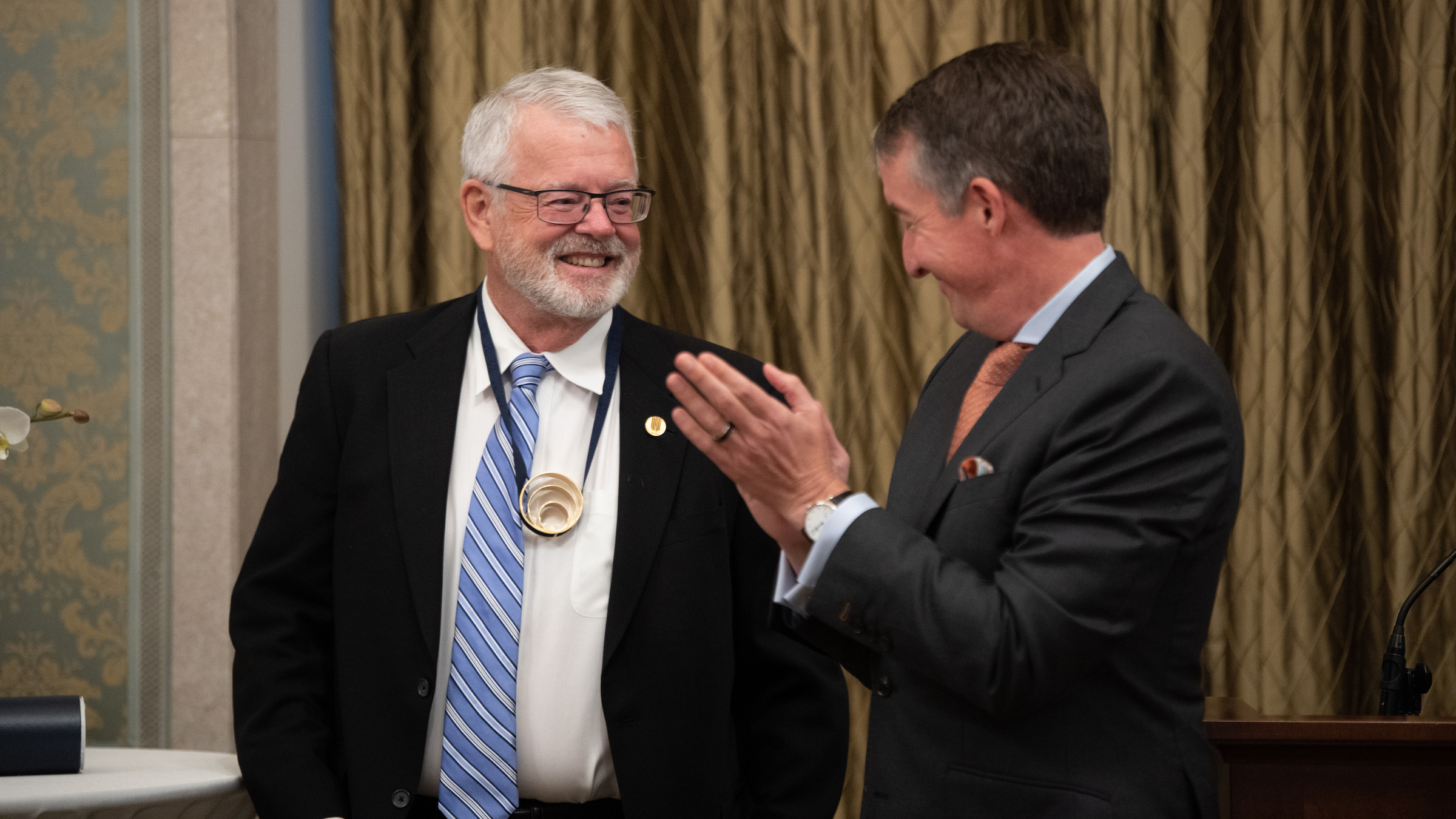 Allan Wolf wears a Wolf Prize medal as UT President Jay Hartzell applauds