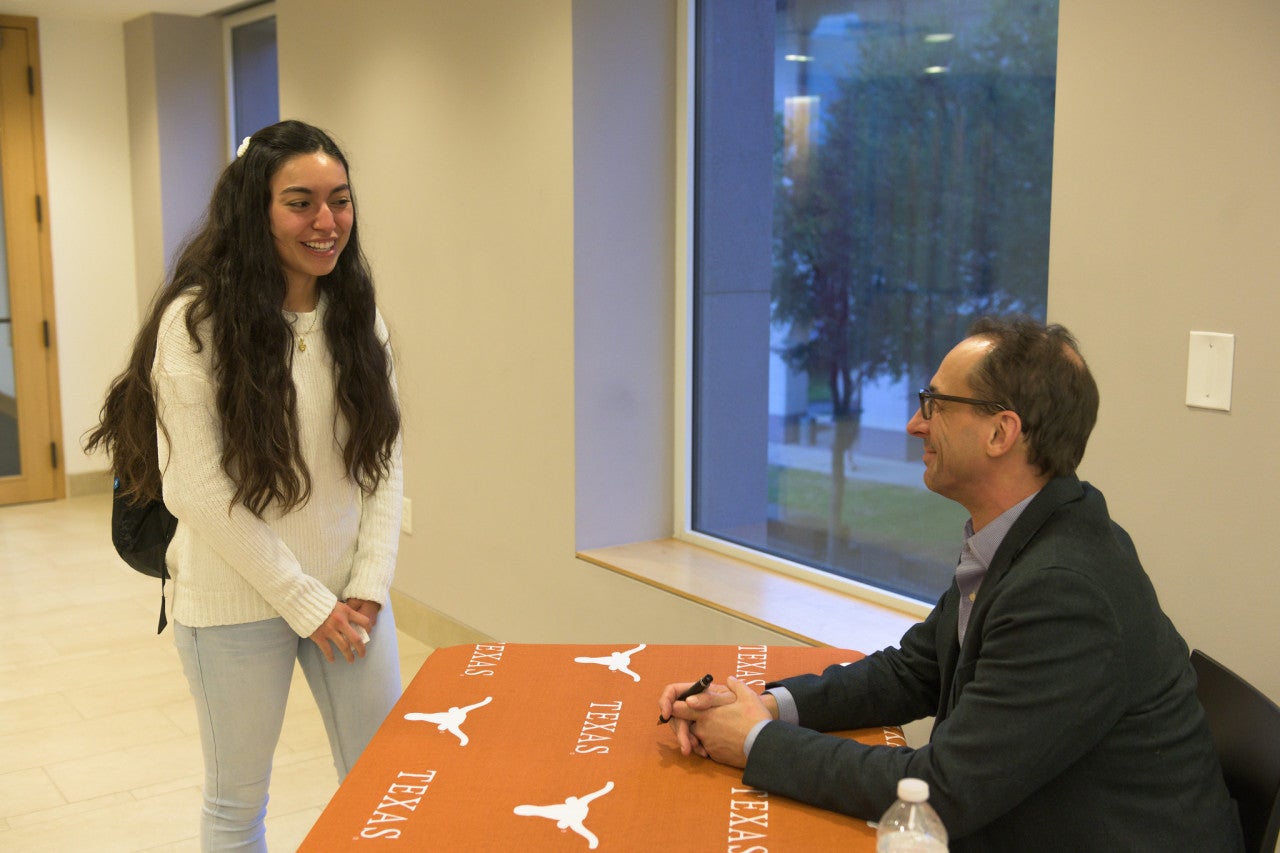 A student talks to an author at a book signing event