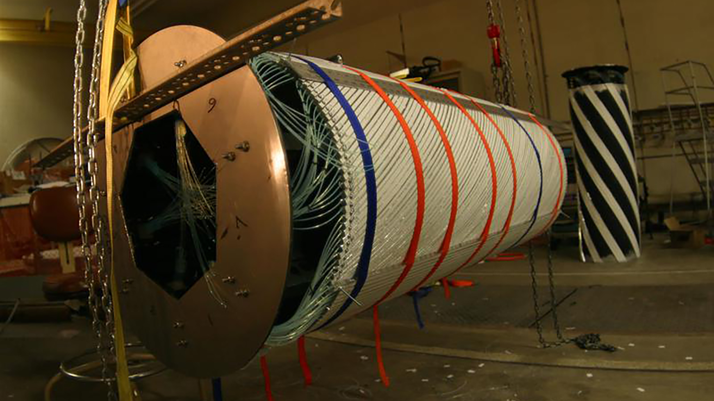 A large cylinder-shaped piece of scientific equipment hangs from chains
