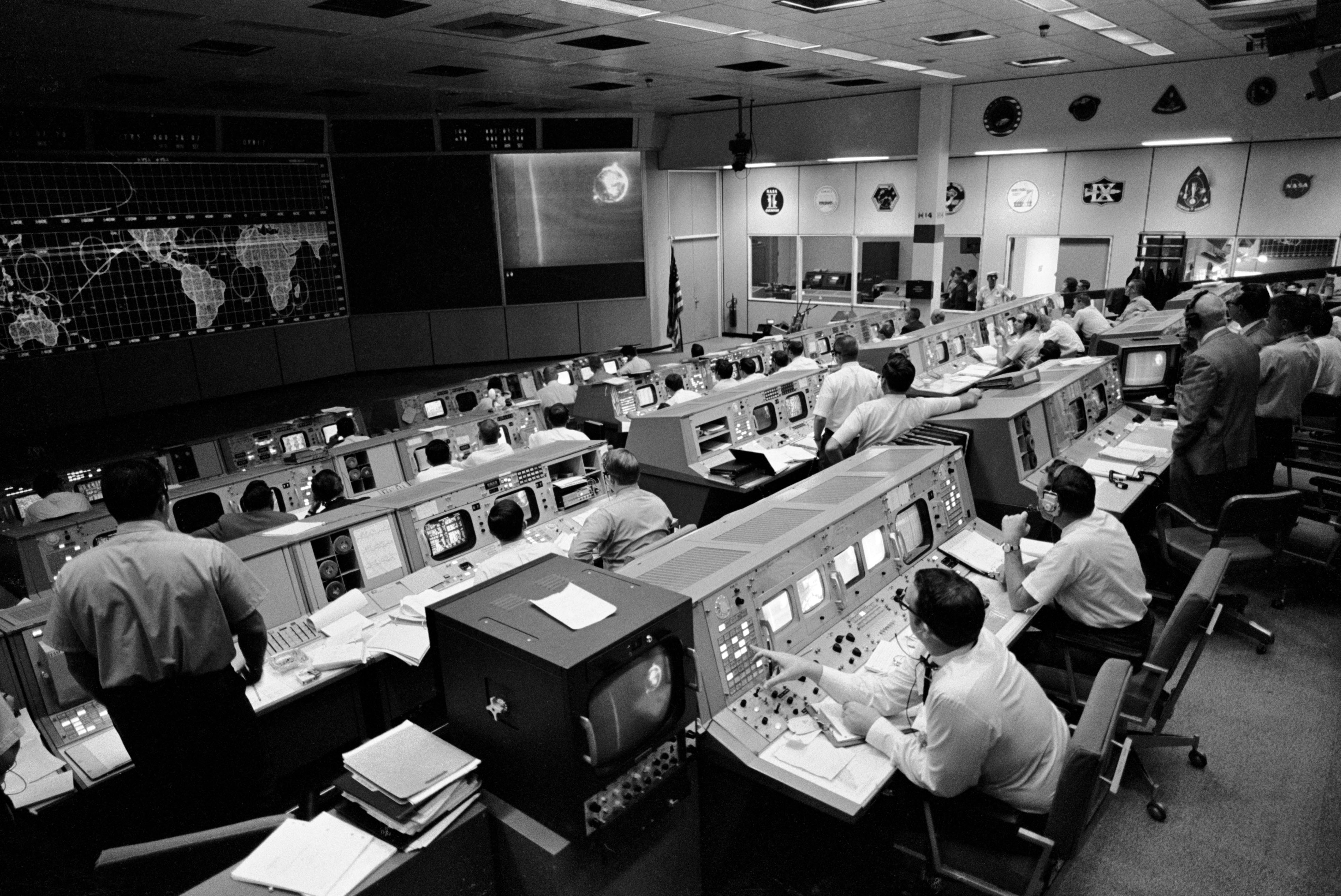 Black and white photo of NASA mission control room with people sitting at rows of computers