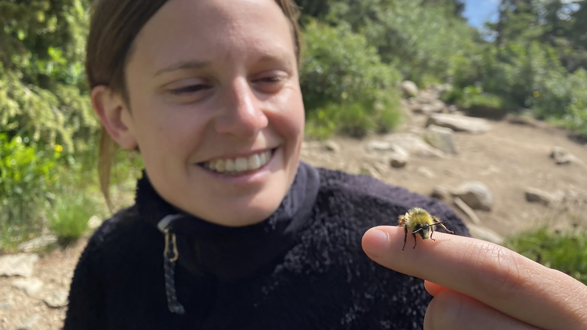 A woman looks at a bee on her finger