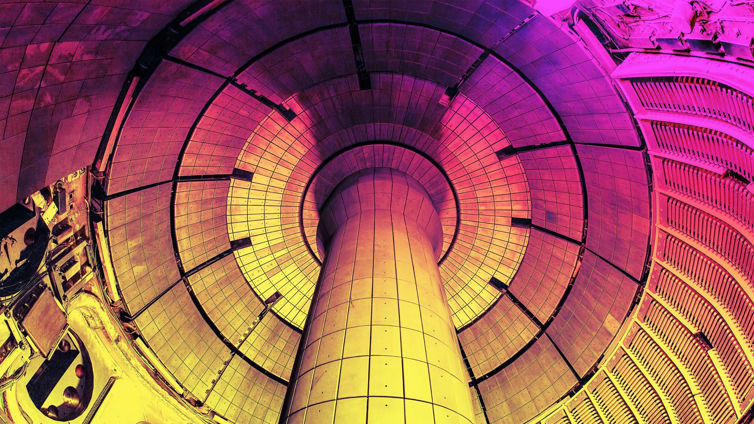 The view inside a tokamak fusion reactor. A curved space inside a donut shape with a central pillar representing filling the donut hole. The metals walls are cast in a rainbow of colors for dramatic effect.