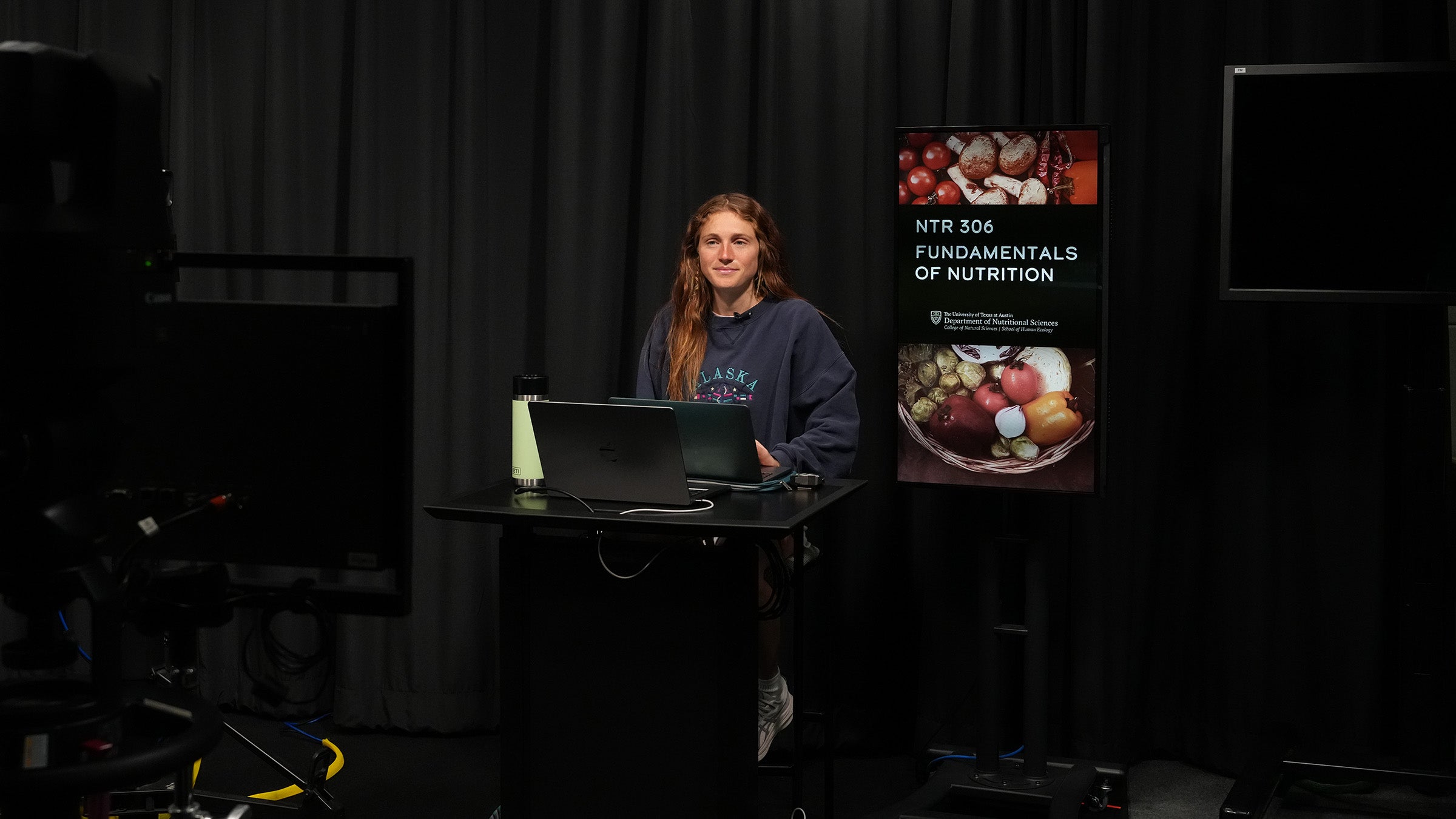 A teaching assistant wears a headset in a video studio