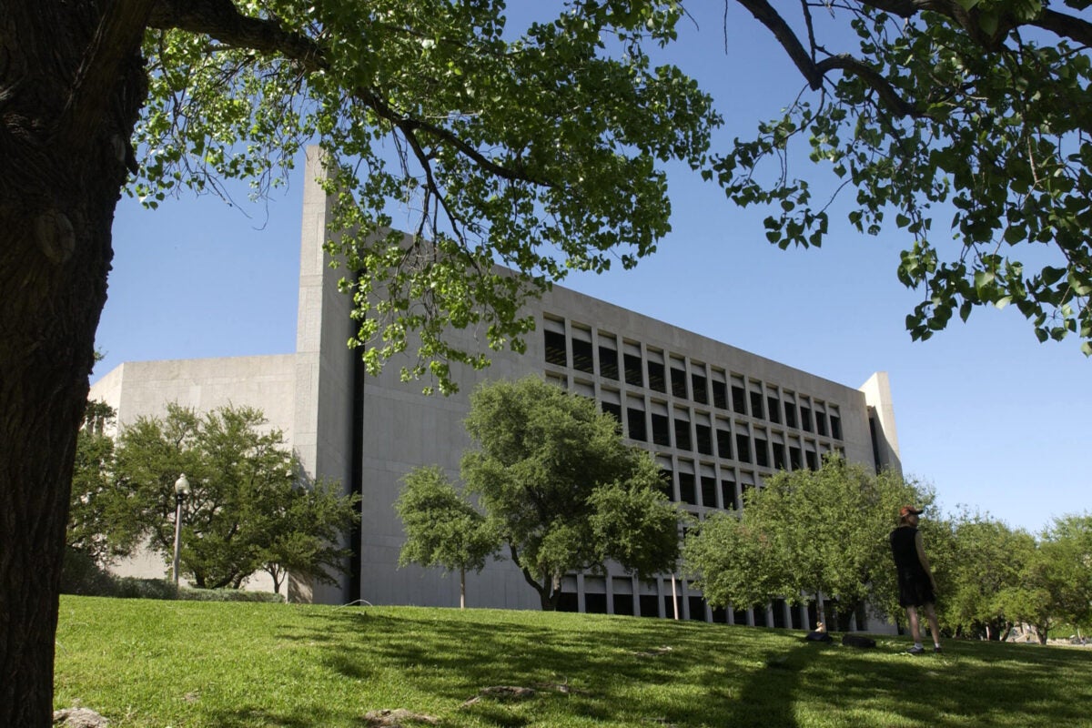 A multistory building on a university campus surrounded by trees