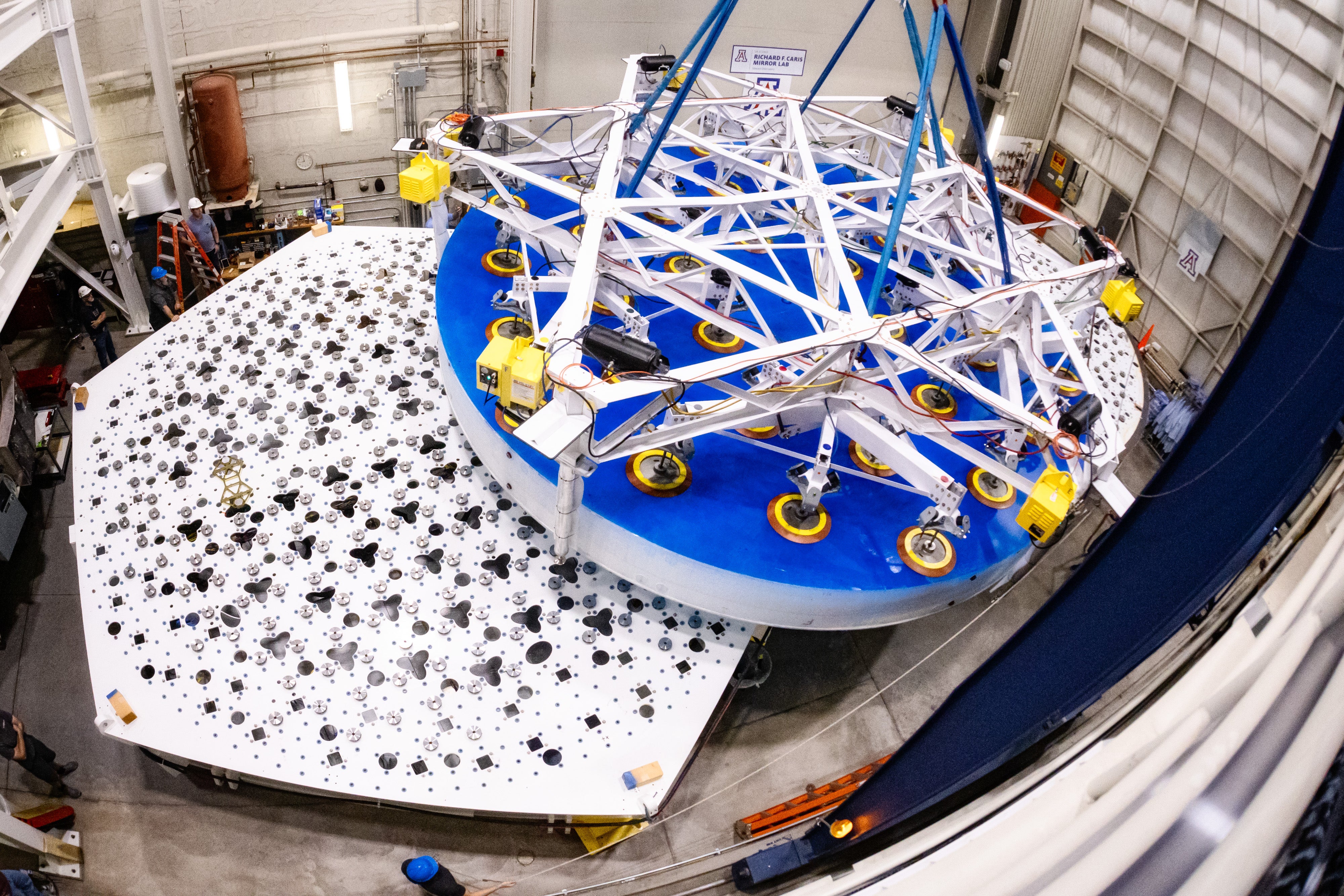 A large telescope mirror hovers over a support system prototype for lab tests