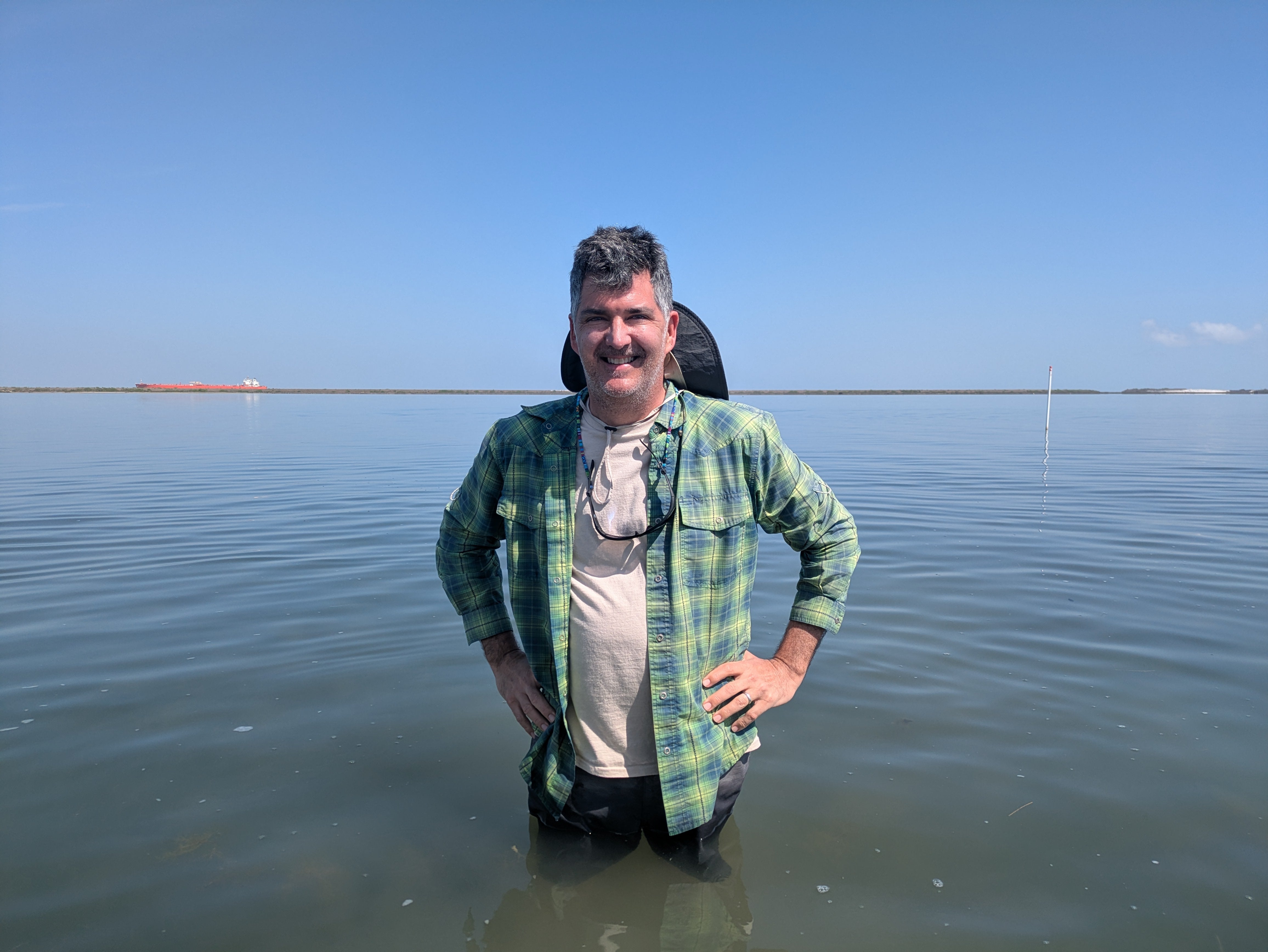 A scientist stands in waist deep water in a seagrass meadow called East Flats, near Port Aransas, Texas.